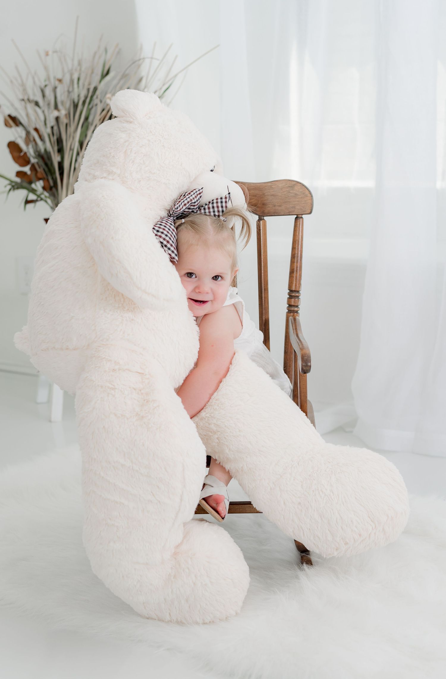 Baby girl holding a giant teddy bear during her Katy, TX Milestone Photo session.