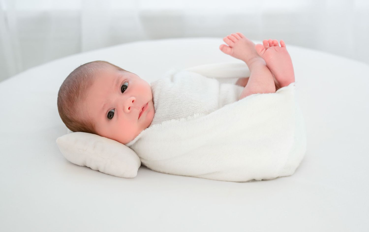 Awake newborn baby wrapped in neutral tones during Katy, Texas studio session.
