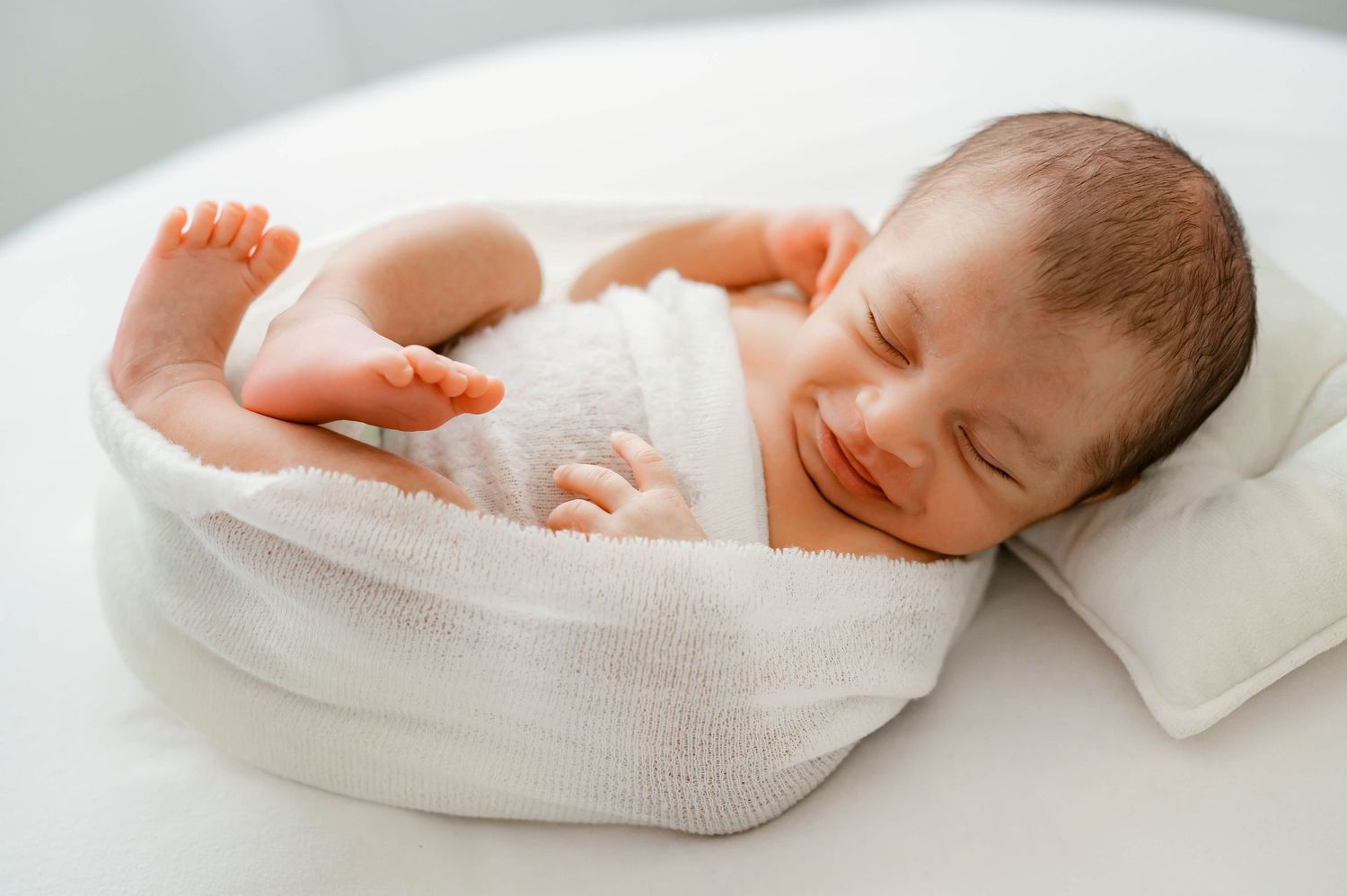 Studio newborn photography in Katy, TX with baby wrapped on white blanket.