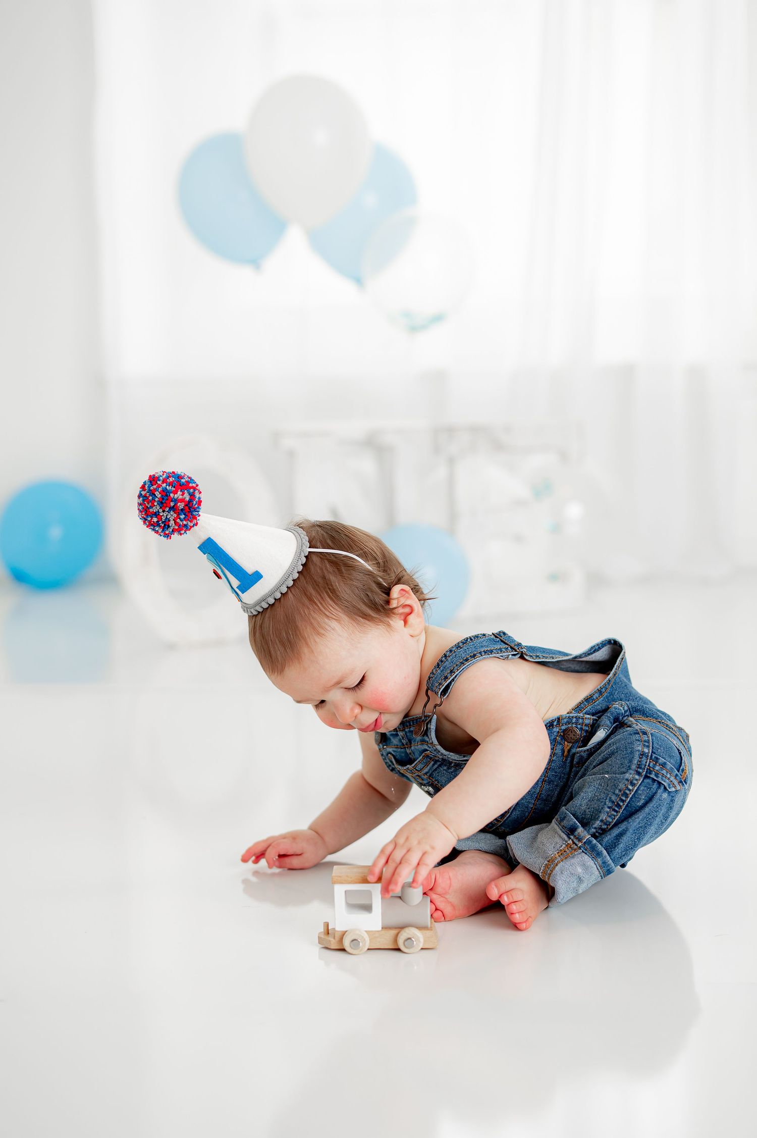 Milestone session with a baby boy playing with a train during his photo session in Katy, TX.