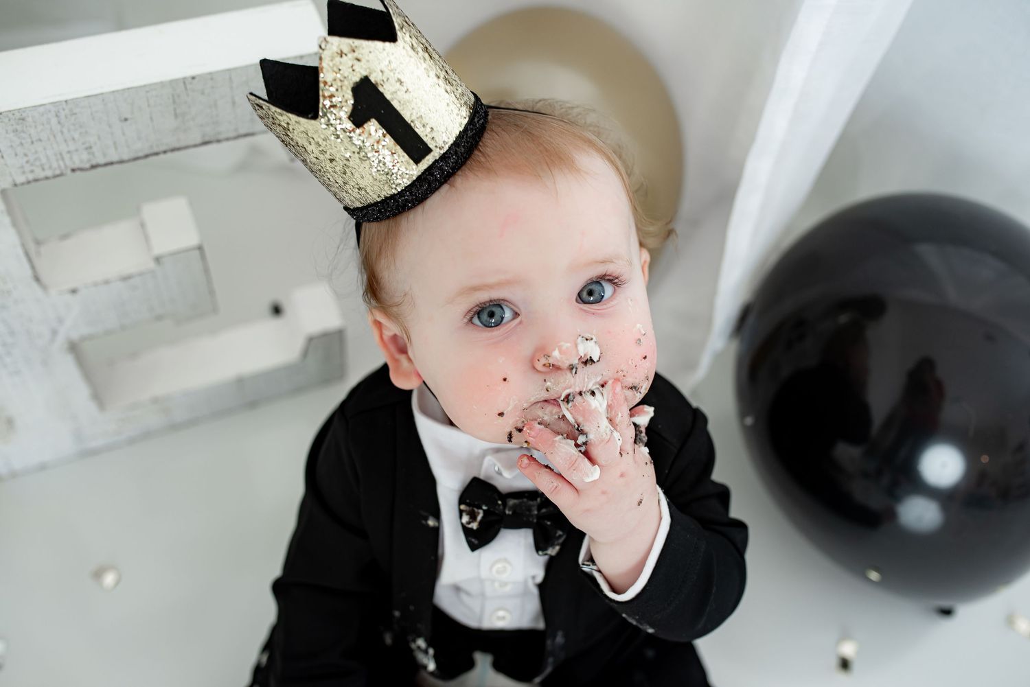 Baby boy eating cake during his cake smash milestone photo session in Katy, TX.