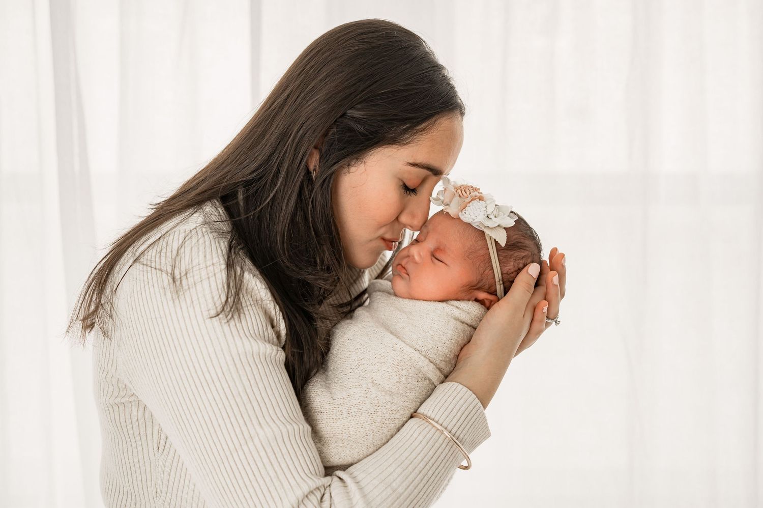 Mother kissing her newborn baby during a natural baby-led session  in Katy Texas Studio.