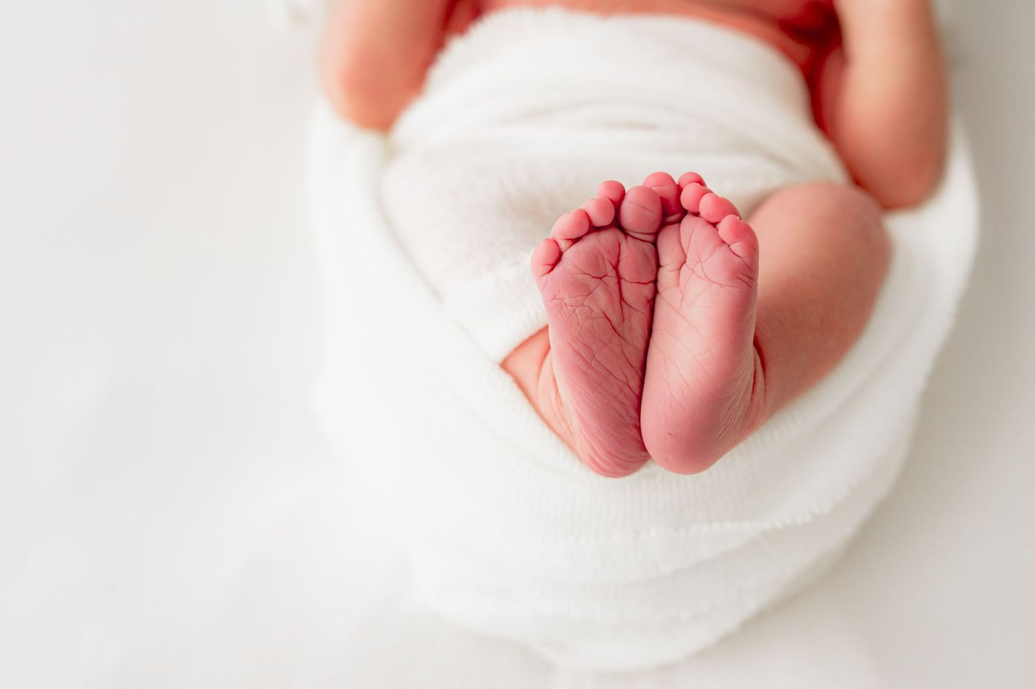 Close up of a newborn baby feet wrapped in neutral tones during a Fulshear, Texas studio session.