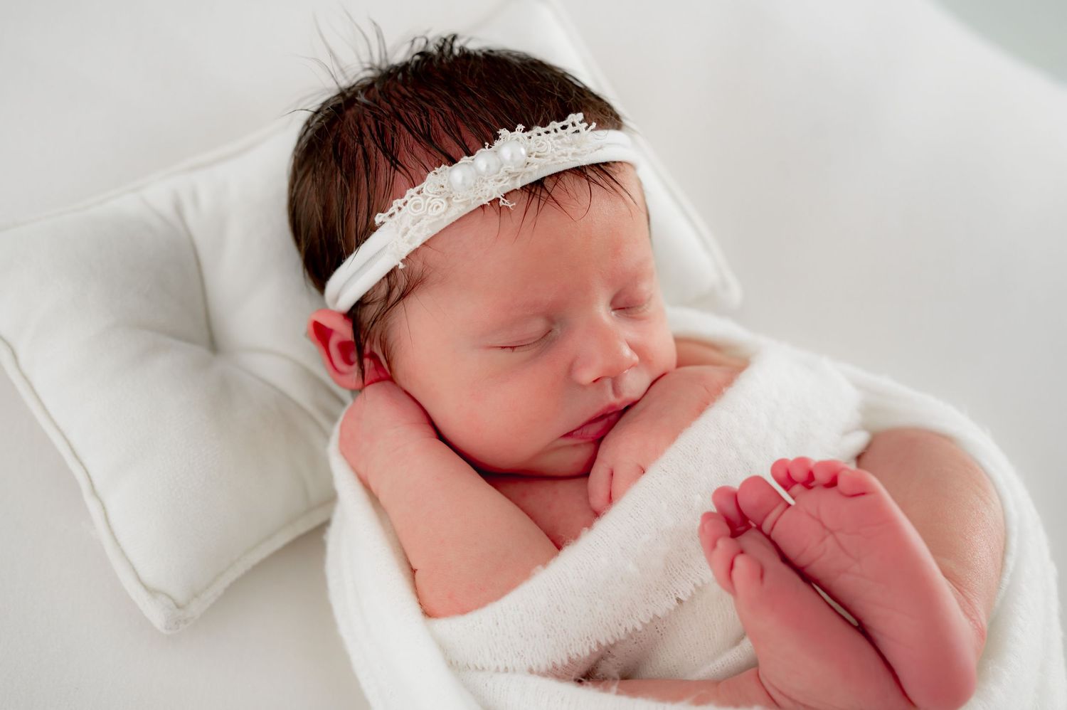 Sleeping wrapped baby with a simple headband during her newborn photography session.