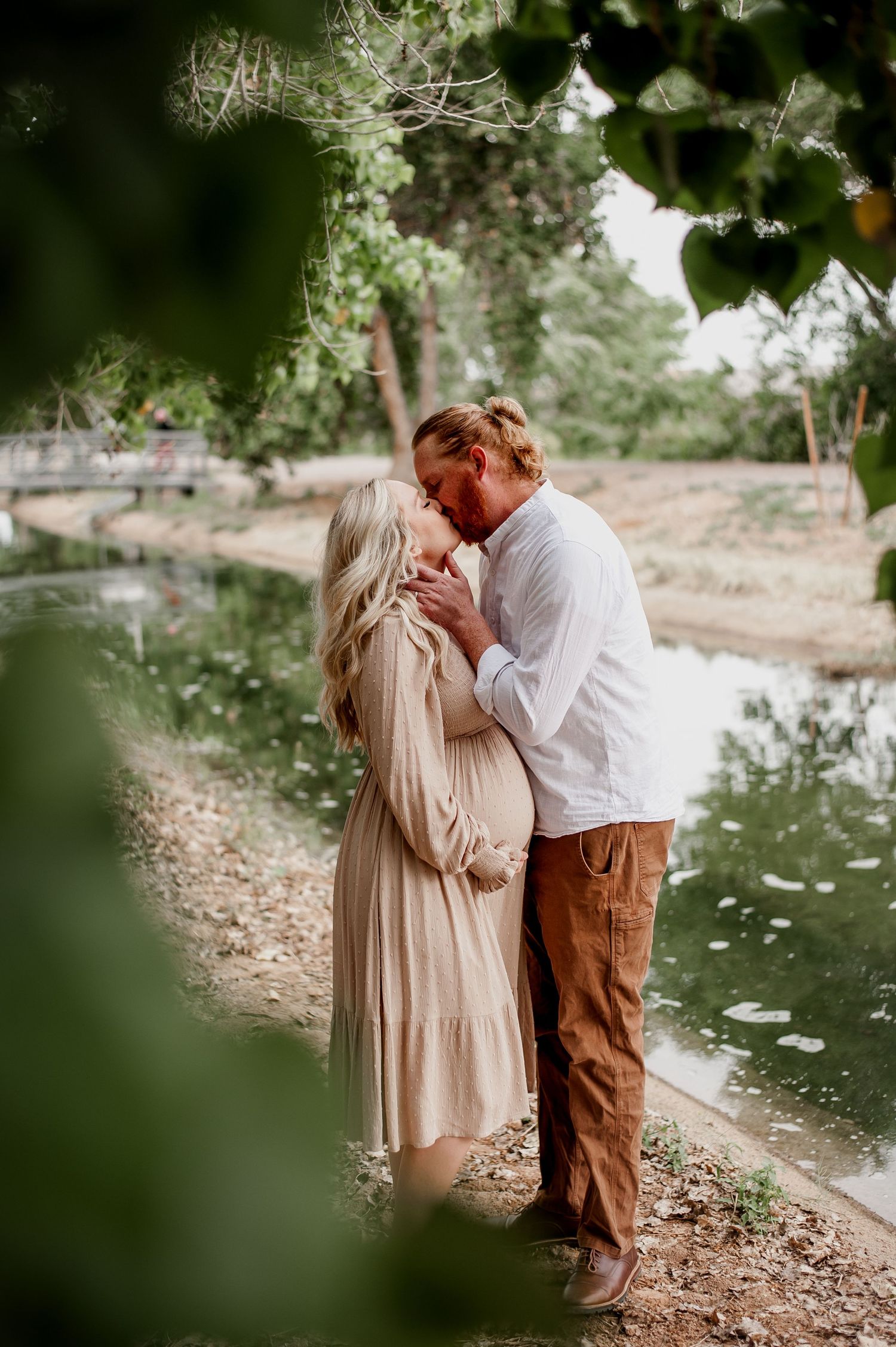 A couple shares intimate moments on a tree-lined path during a romantic outdoor photoshoot.
