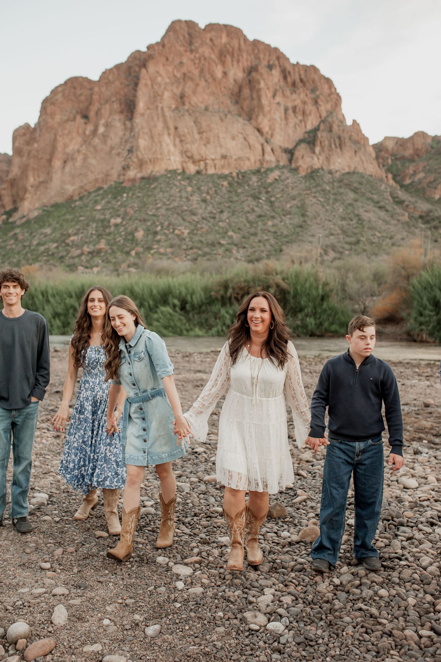 A group poses for a photo in front of a majestic desert mountain landscape with rocky terrain.