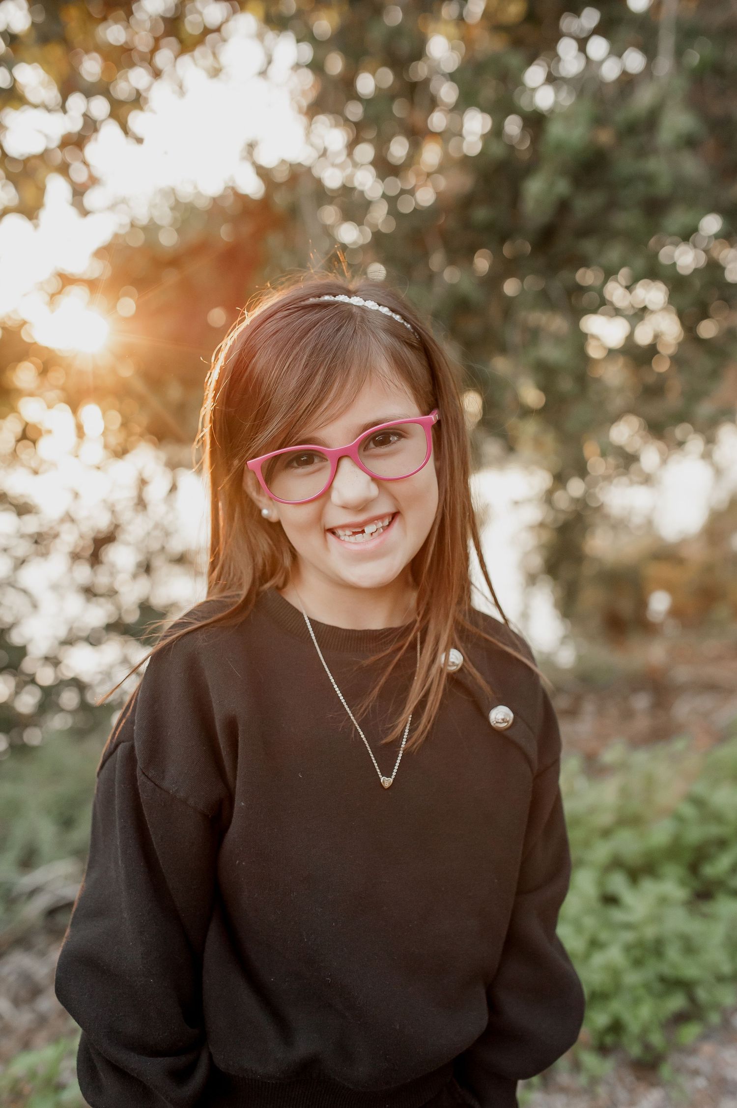 A series of four outdoor portrait shots featuring someone wearing a black sweater and red glasses against a natural backdrop.