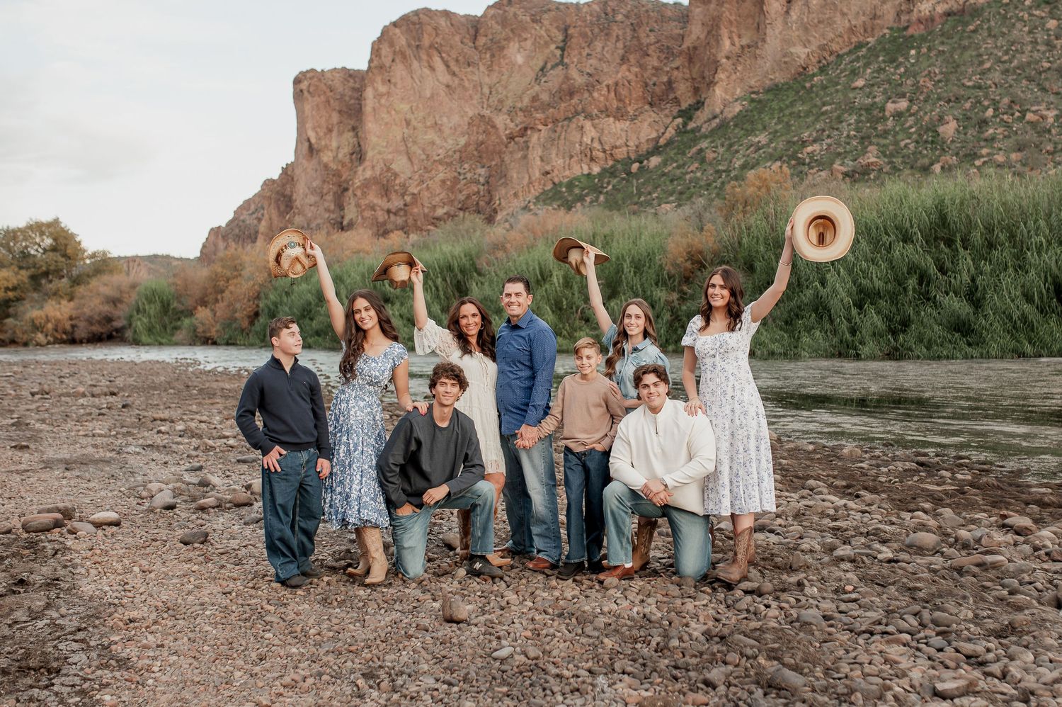 A group of people sitting on rocks near a scenic canyon with desert cliffs in the background.