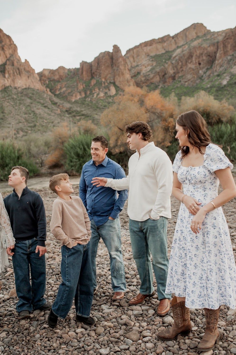 Family of five posing outdoors near rocky terrain with mountain backdrop in Arizona desert landscape.