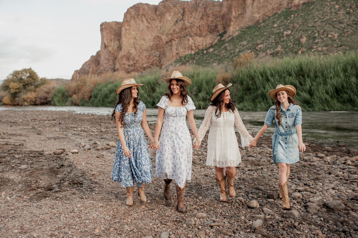 A group walks together along a scenic desert canyon path with towering red rock cliffs in the background.