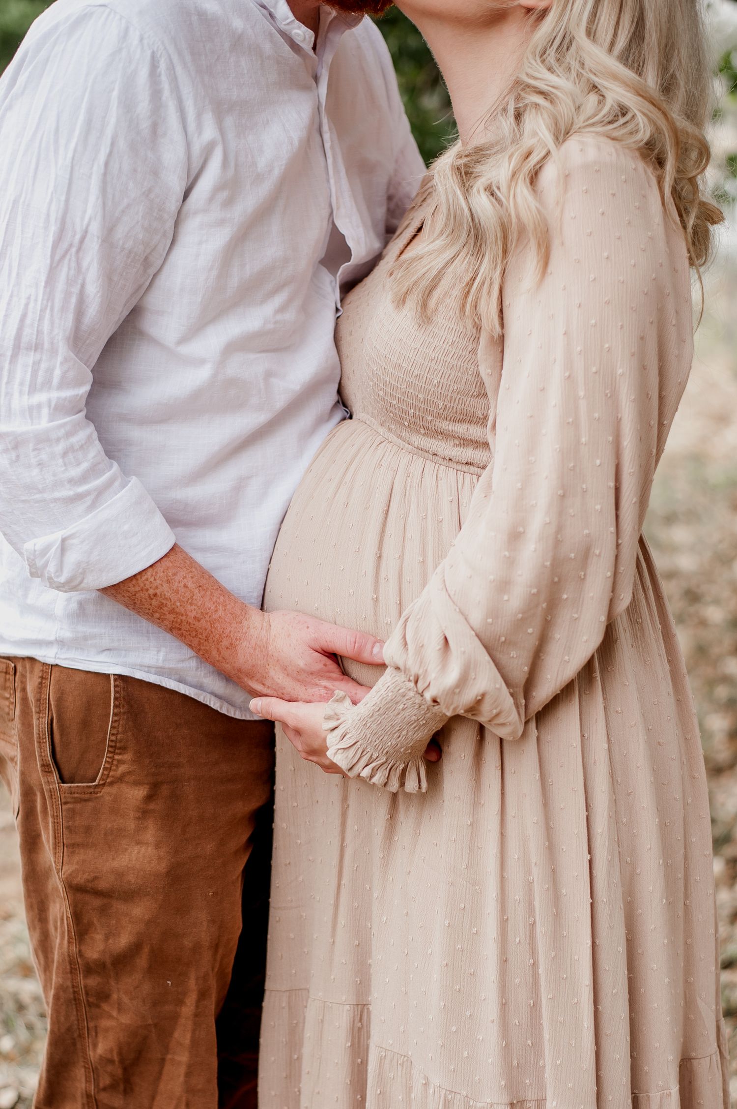 Close-up maternity photos showing tender moments between a couple in neutral beige and brown clothing.