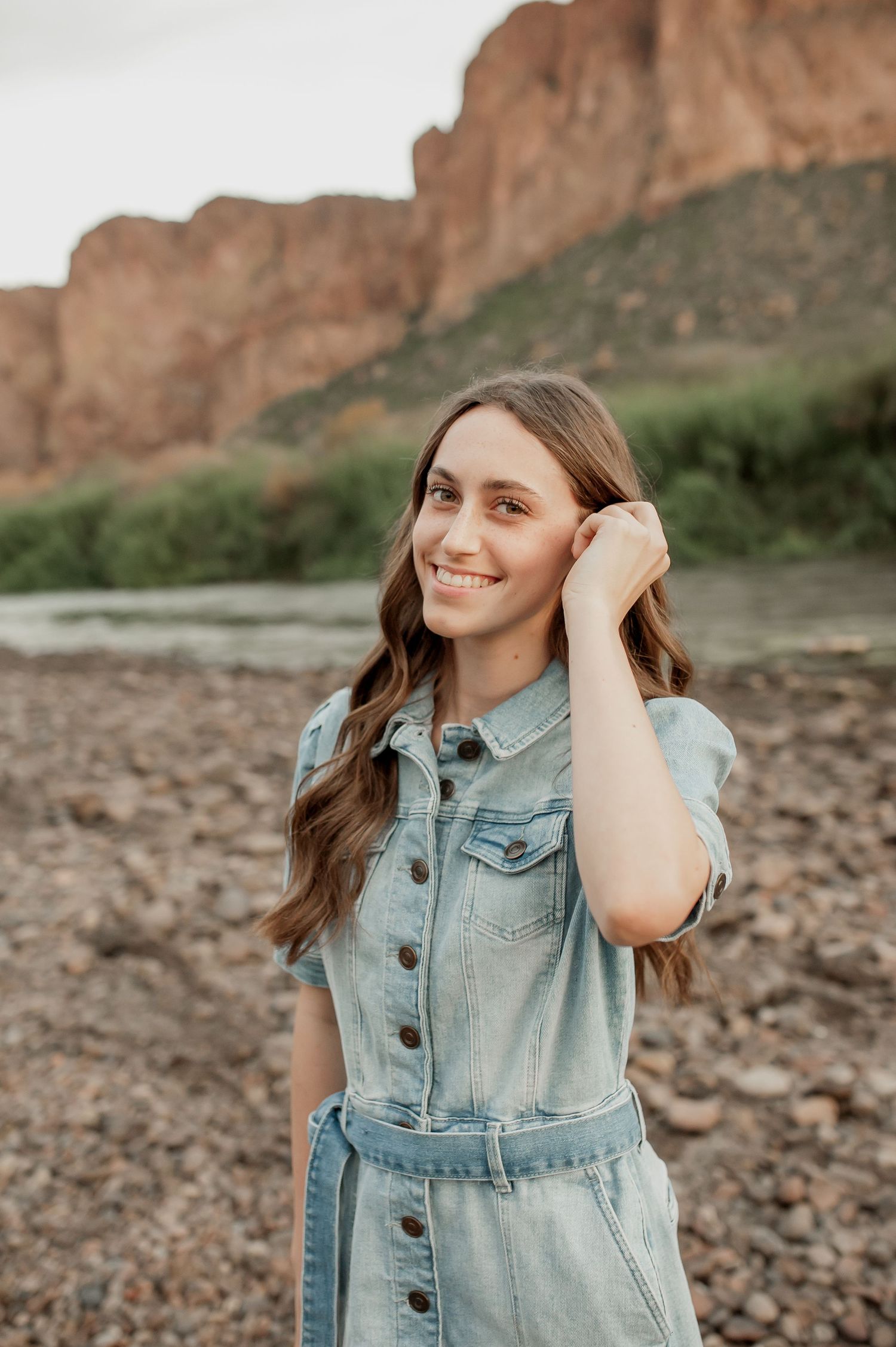A candid portrait shot in front of scenic desert cliffs with warm lighting and natural scenery.
