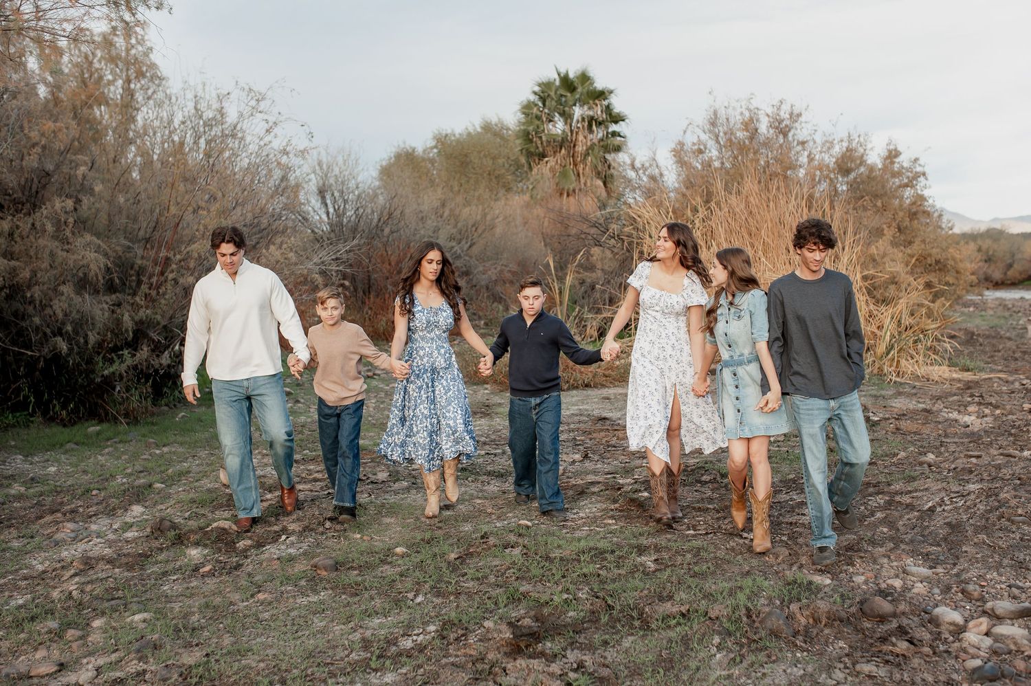 Group of people walking together on a rustic outdoor path during autumn wearing casual clothing.