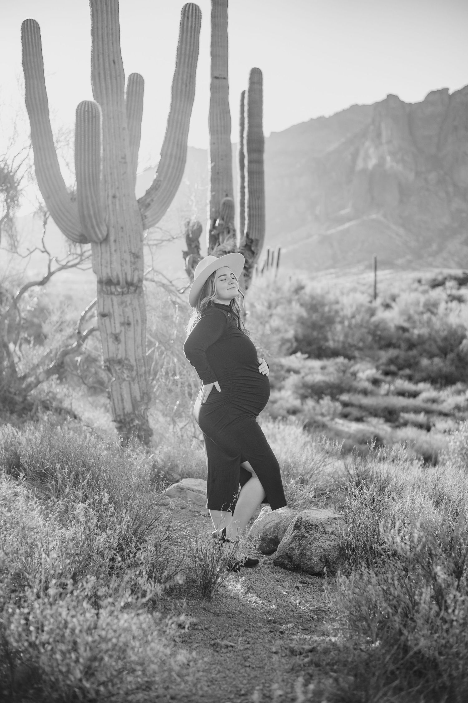 Black and white desert scene with couple dancing among towering saguaro cacti and desert brush.