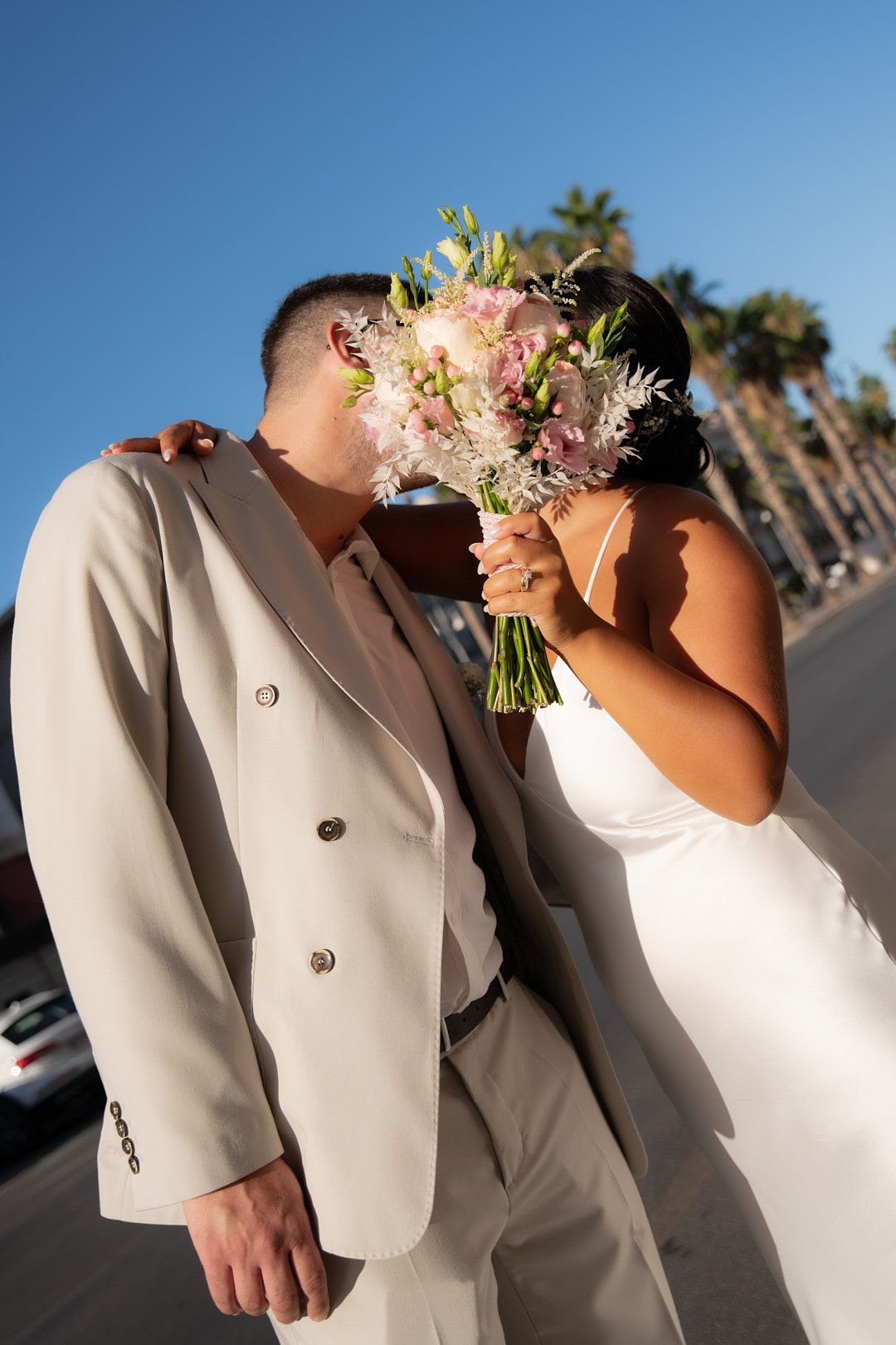 Wedding party members in white dresses and beige suits standing together.
