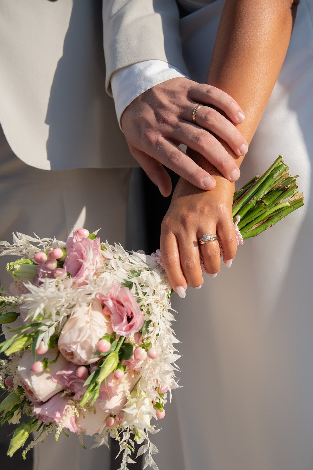 Close-up of hands holding a delicate pink and white wedding bouquet.