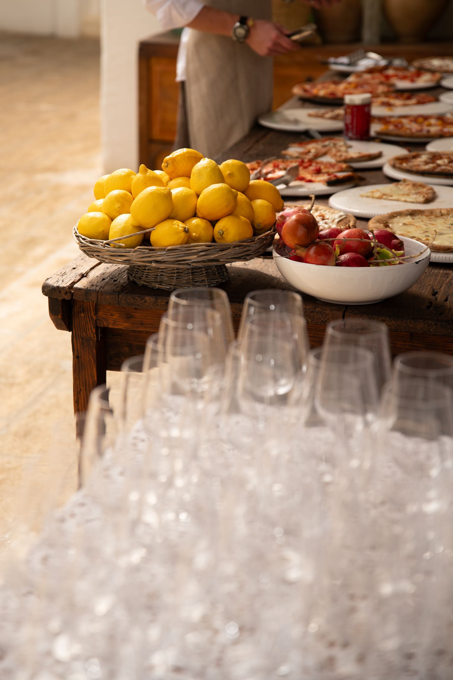 Fresh lemons and wine glasses arranged on a rustic wooden table at a catering event.