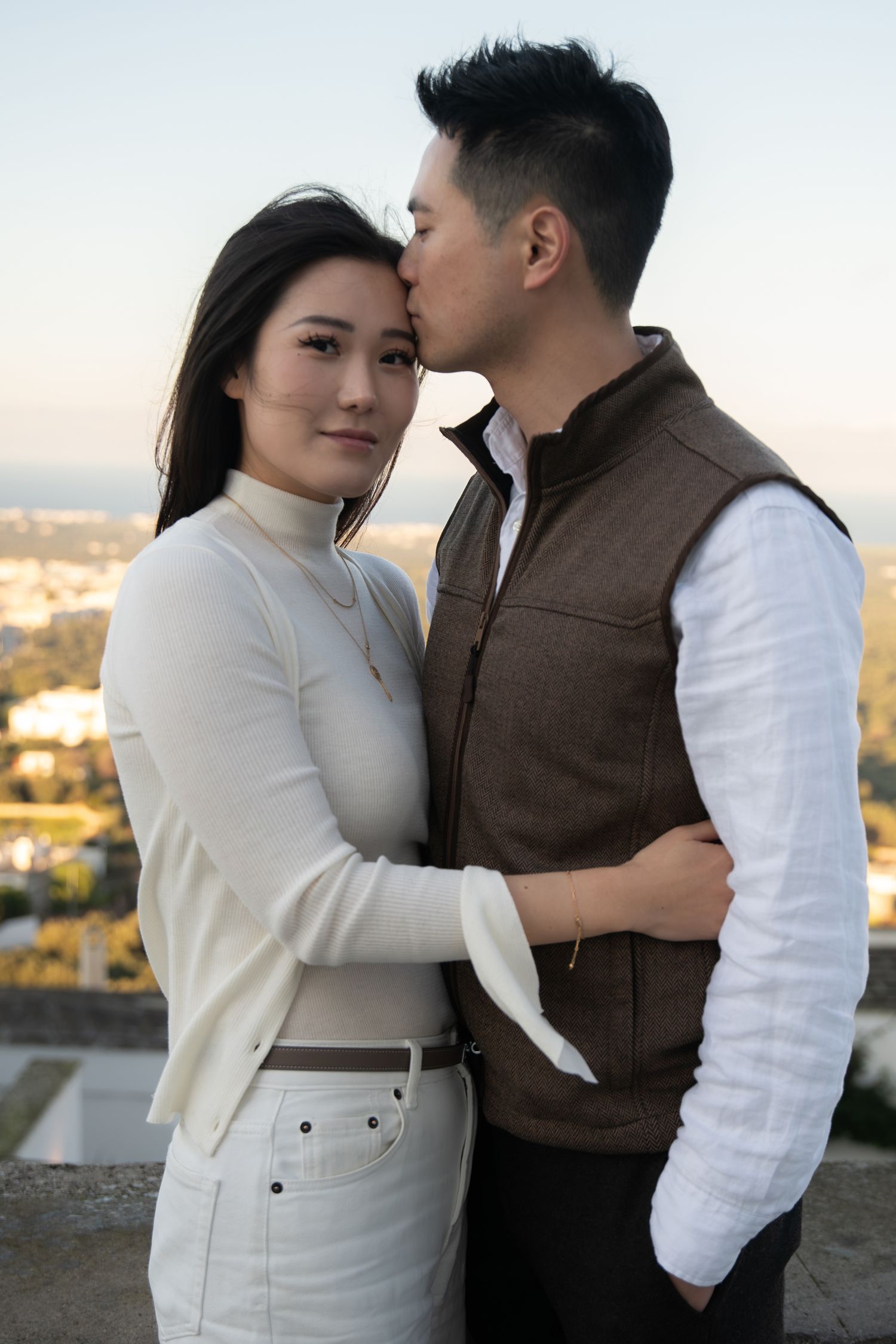 A tender embrace captured against a city backdrop at golden hour.