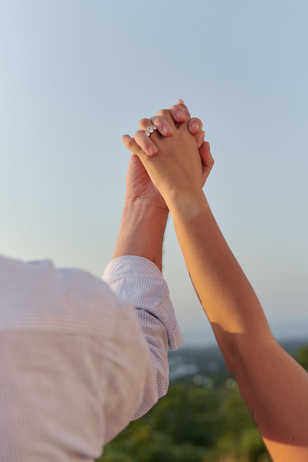 Two hands joined together against a bright blue sky background.