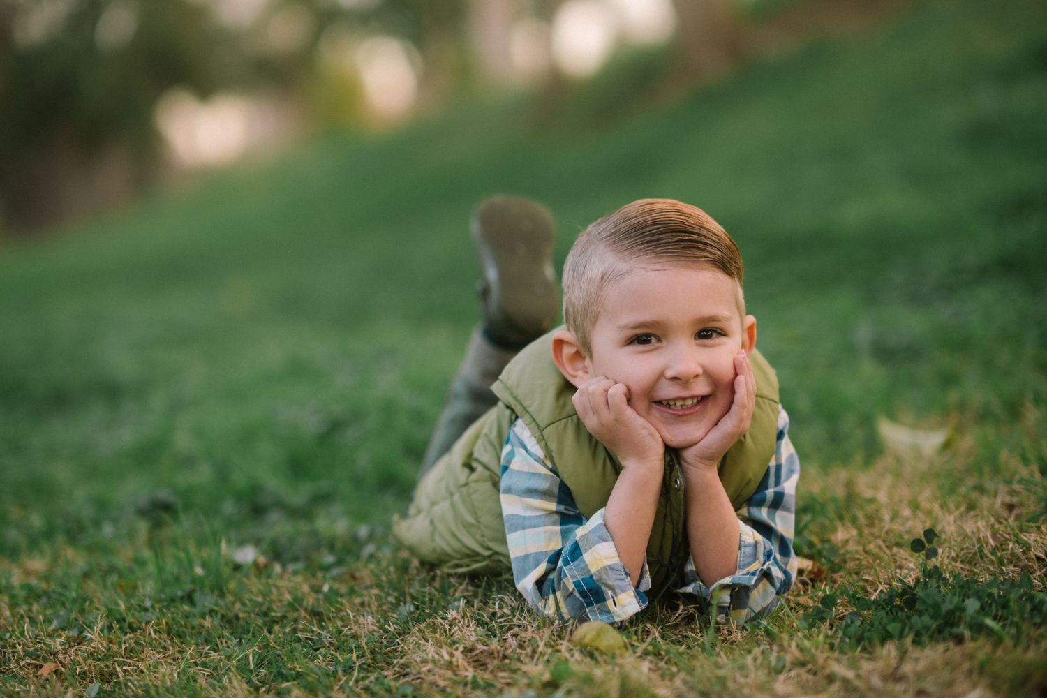 Child lying on green grass enjoying a relaxed outdoor moment.