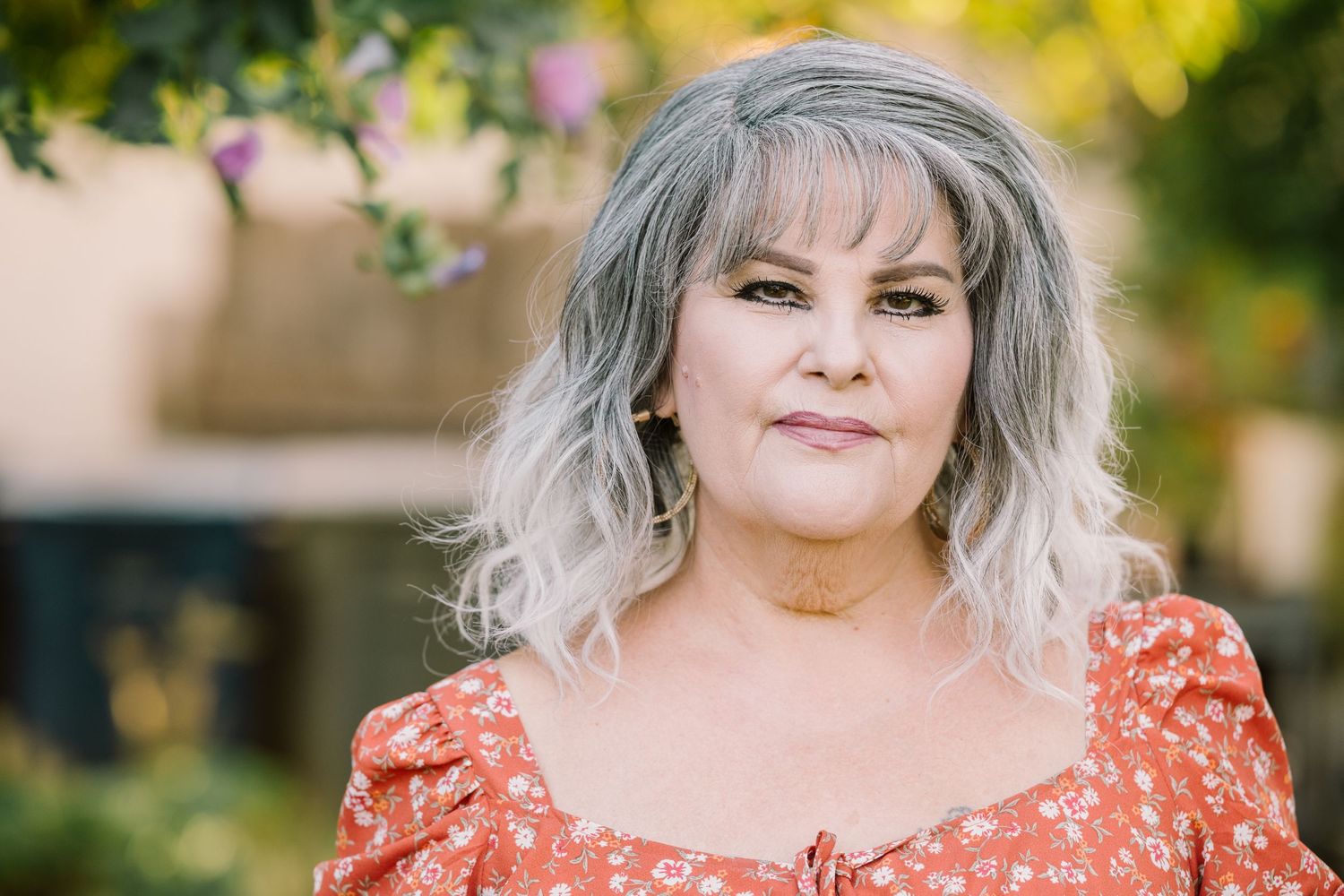 Woman in coral dress poses for outdoor portrait series with soft natural lighting.