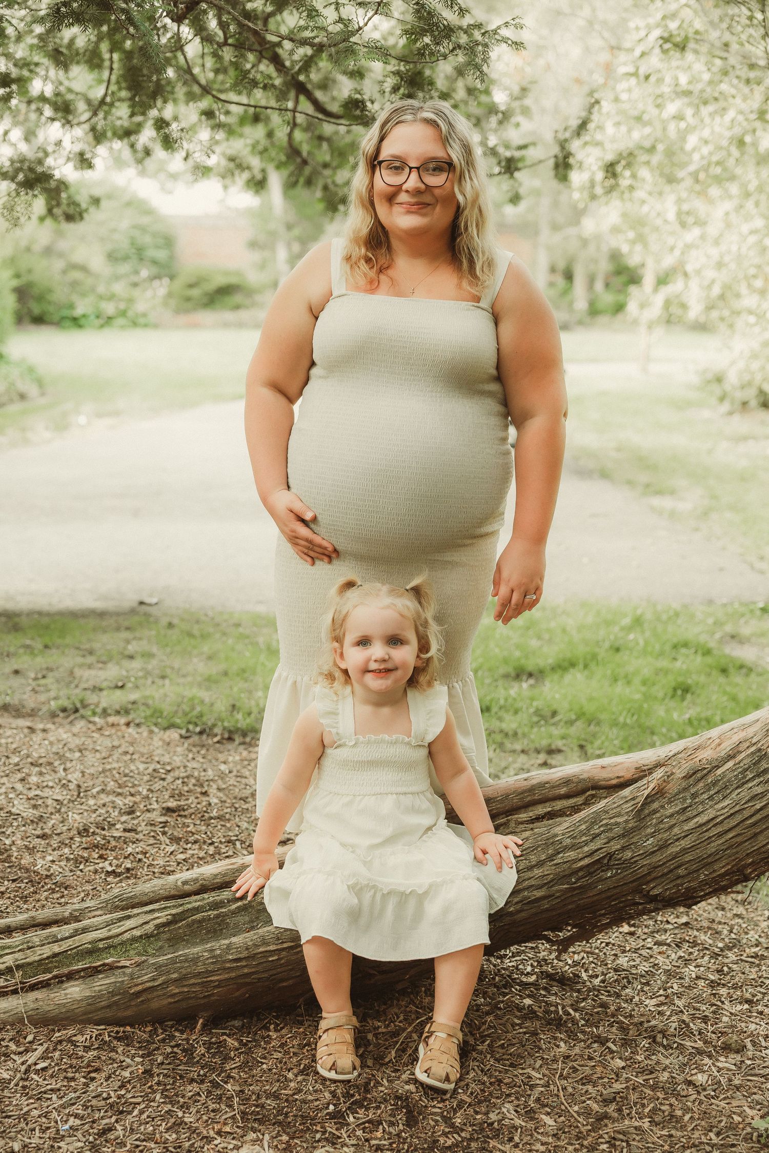 Natural outdoor family portraits taken near fallen tree in park setting.
