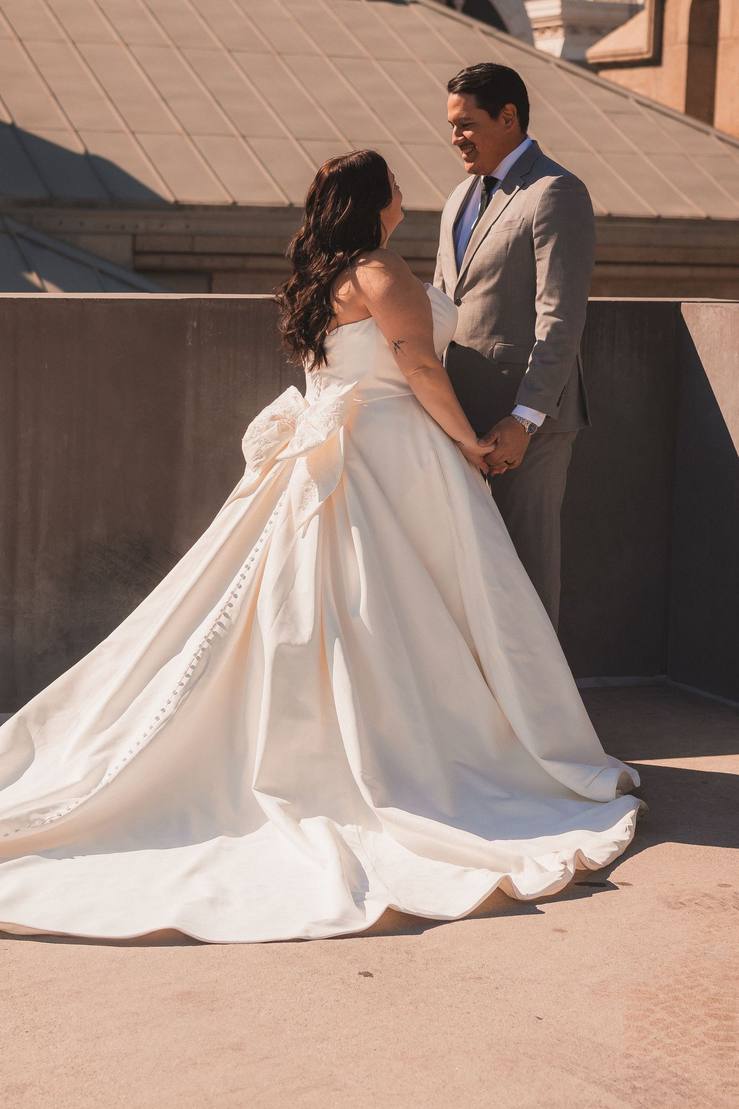 Beautiful wedding dress with full skirt spreads across stone steps during outdoor photoshoot.