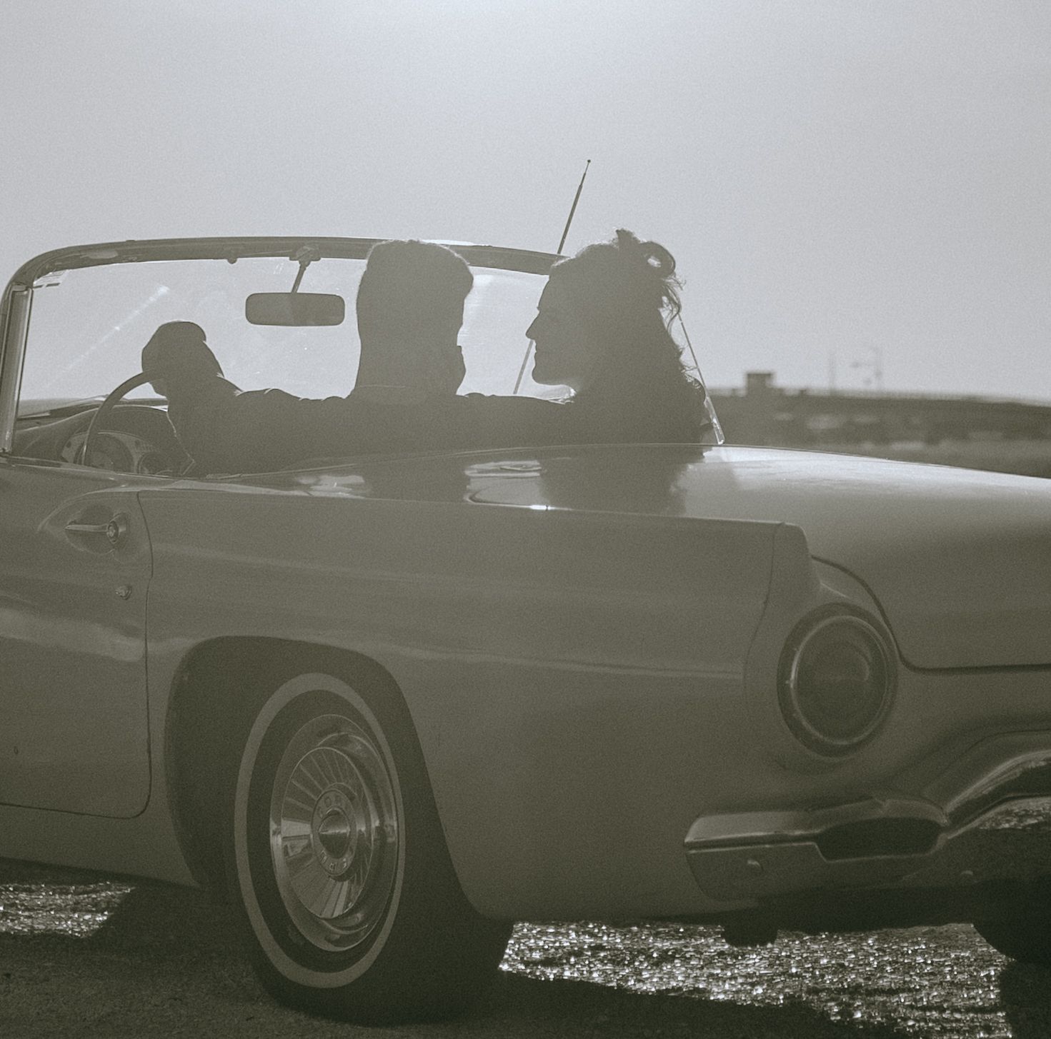 Vintage car silhouettes lined up against a misty horizon in black and white.