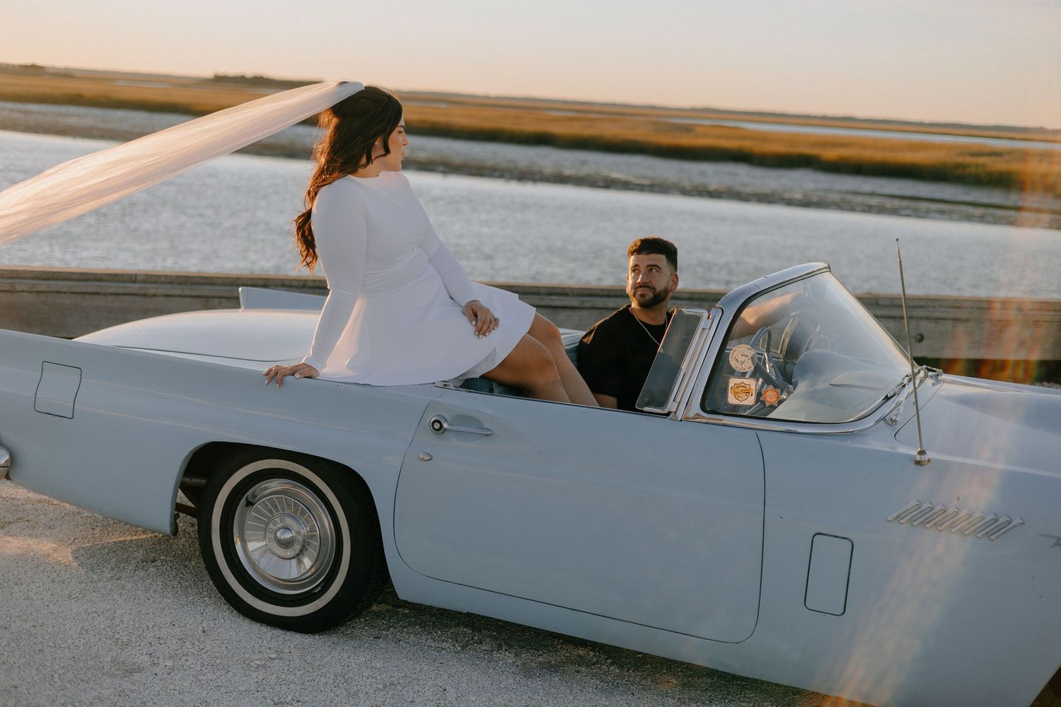 Classic white convertible car with chrome trim and whitewall tires photographed at sunset against a desert landscape.