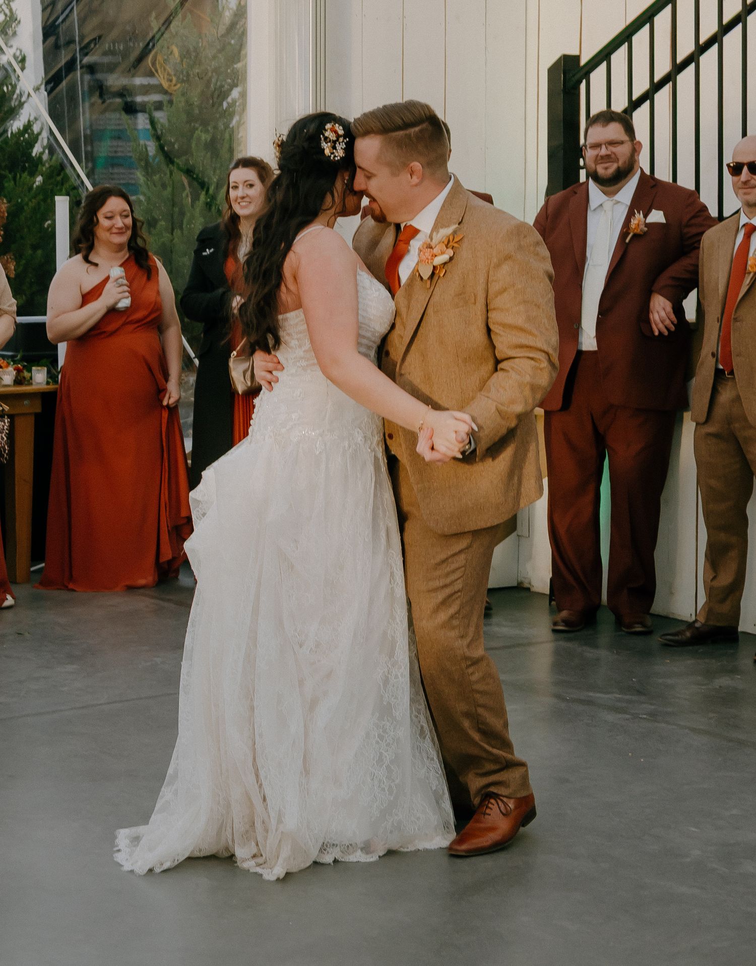 A newlywed couple shares their first dance surrounded by wedding guests.
