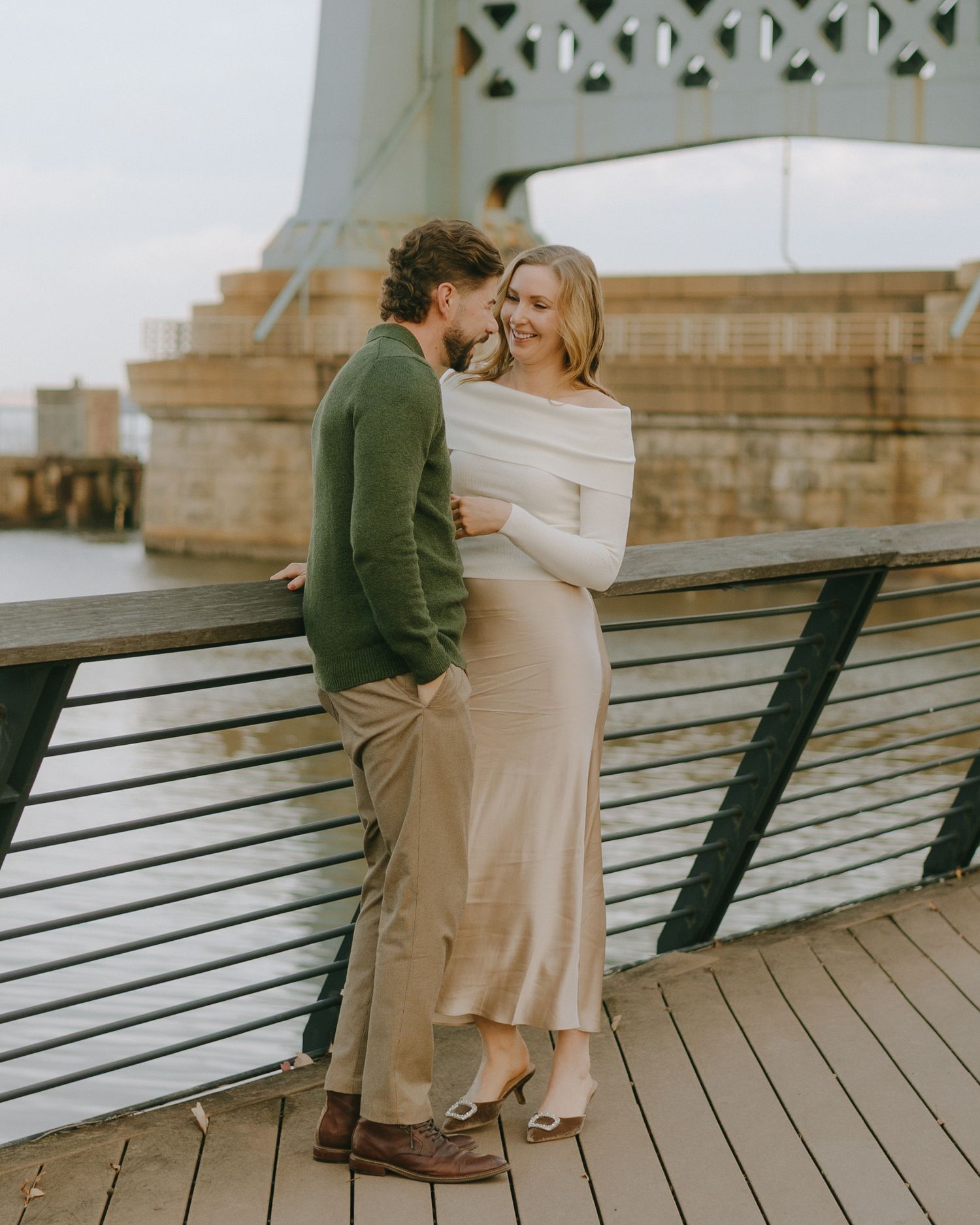 A couple shares an intimate moment while sitting on a wooden bench at a scenic overlook.