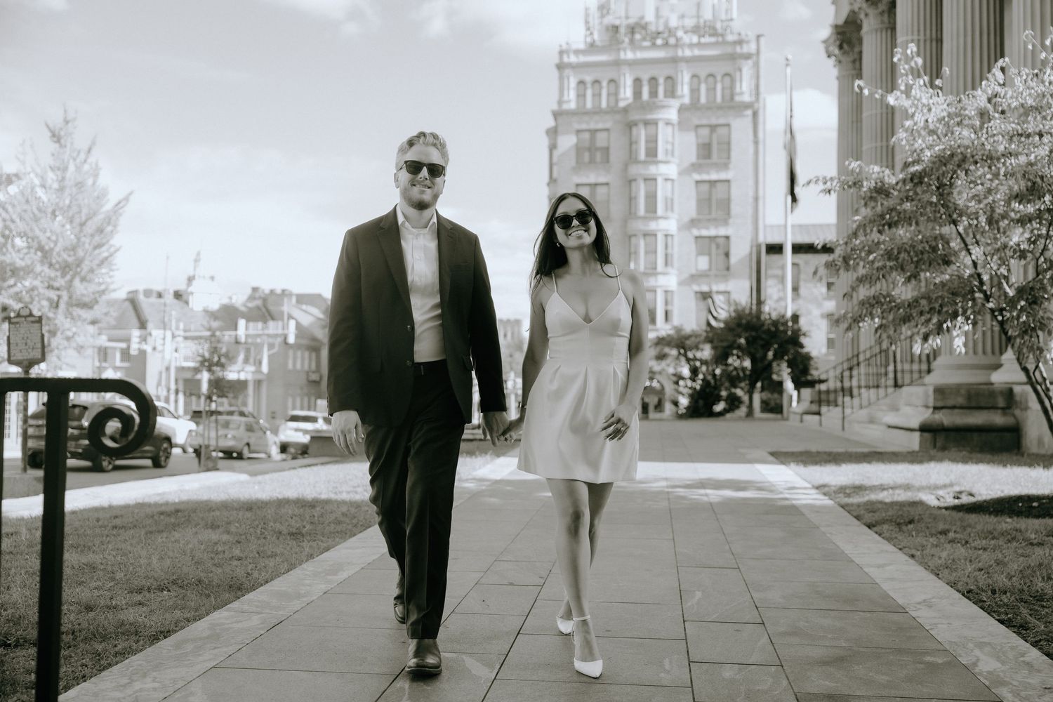Artistic black and white photo series showing a couple walking together outside a classic building with white columns.
