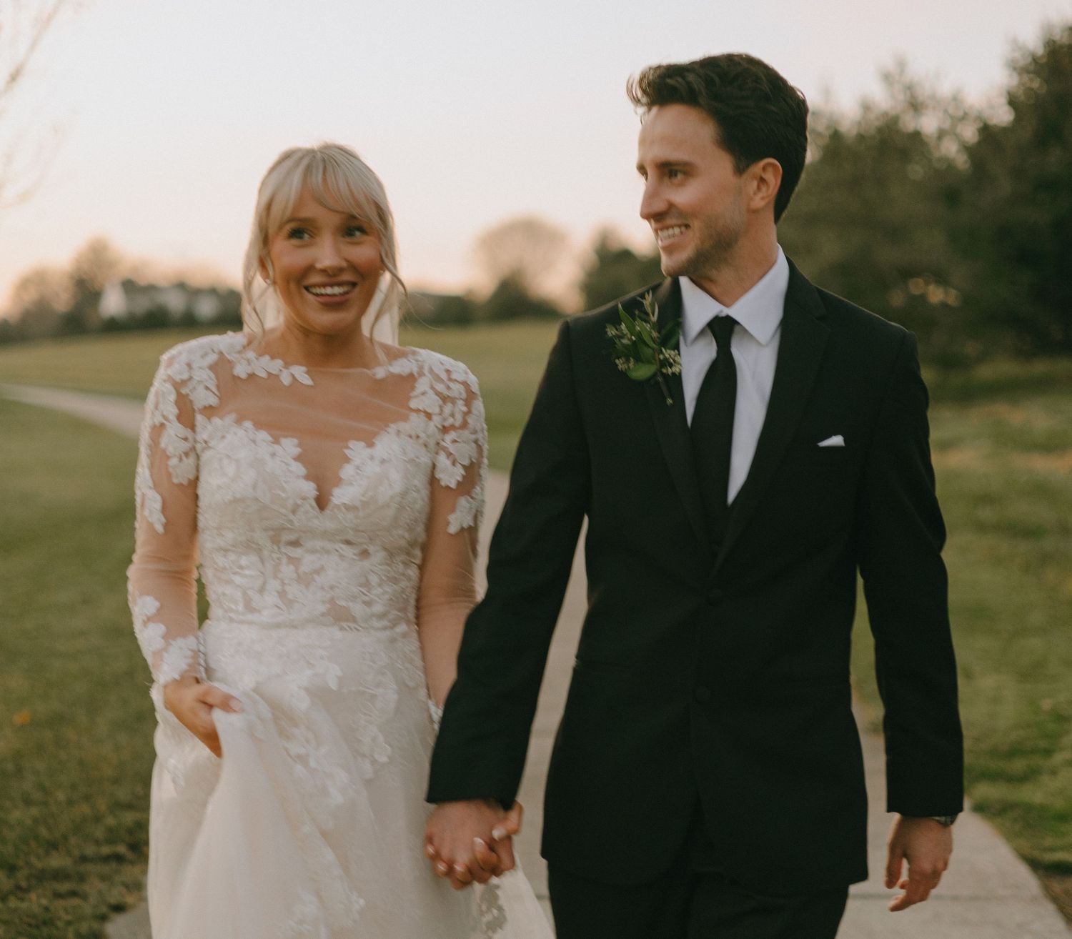 A couple holds hands while walking together during their outdoor wedding photoshoot.