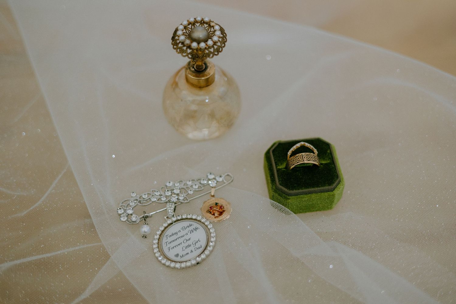 Wedding accessories including jewelry, perfume bottles, and delicate details arranged on white fabric.