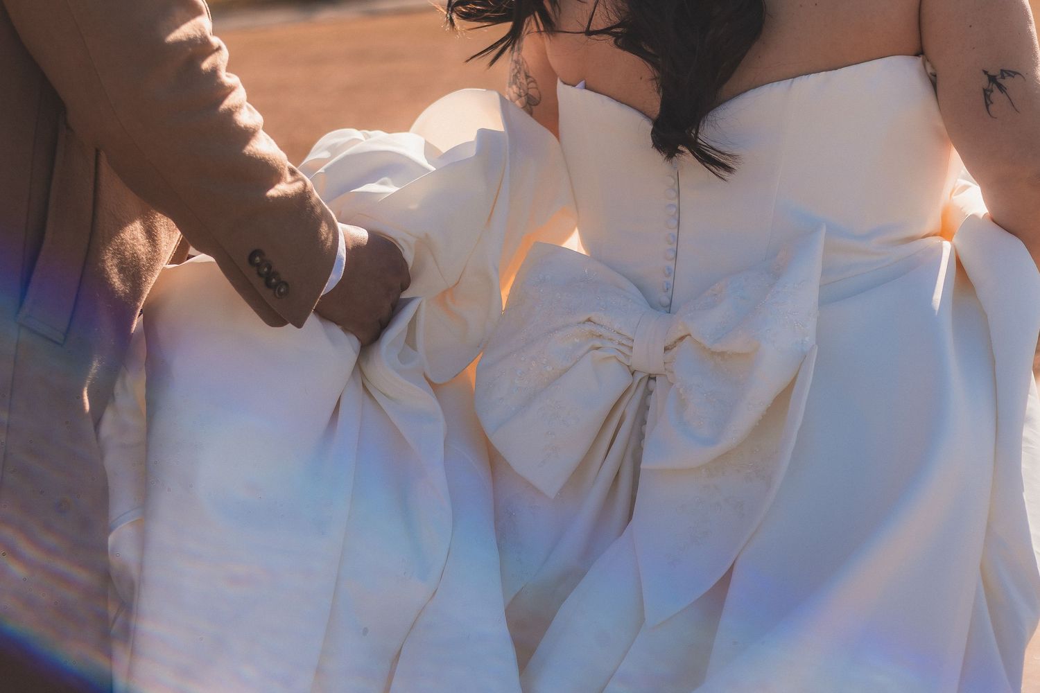 White wedding gown with an oversized bow detail cascading down steps in beautiful natural lighting.