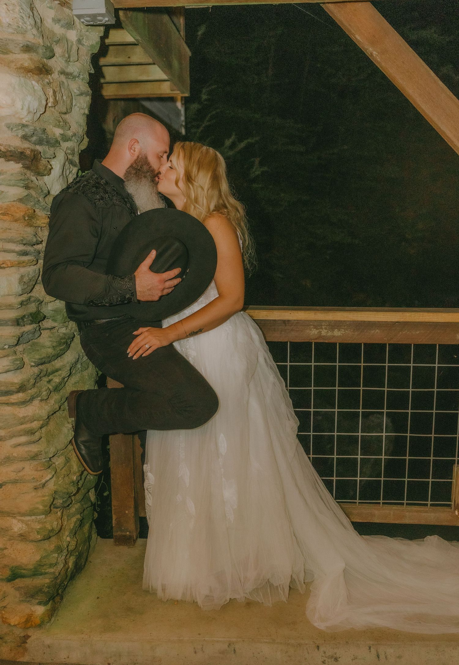 An intimate wedding moment captured against a rustic stone wall backdrop.