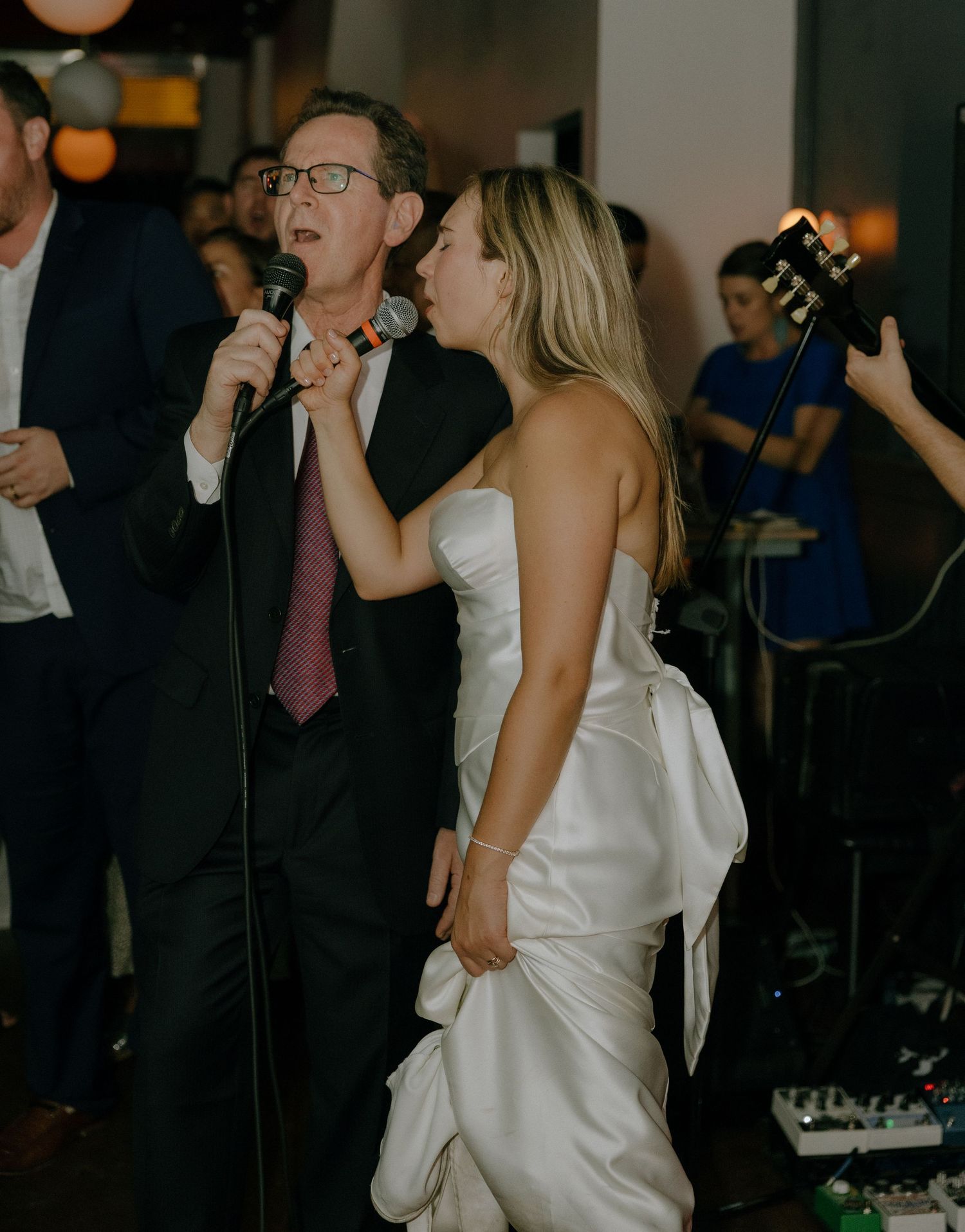 Wedding celebration featuring karaoke performances and dancing in a dimly lit venue.