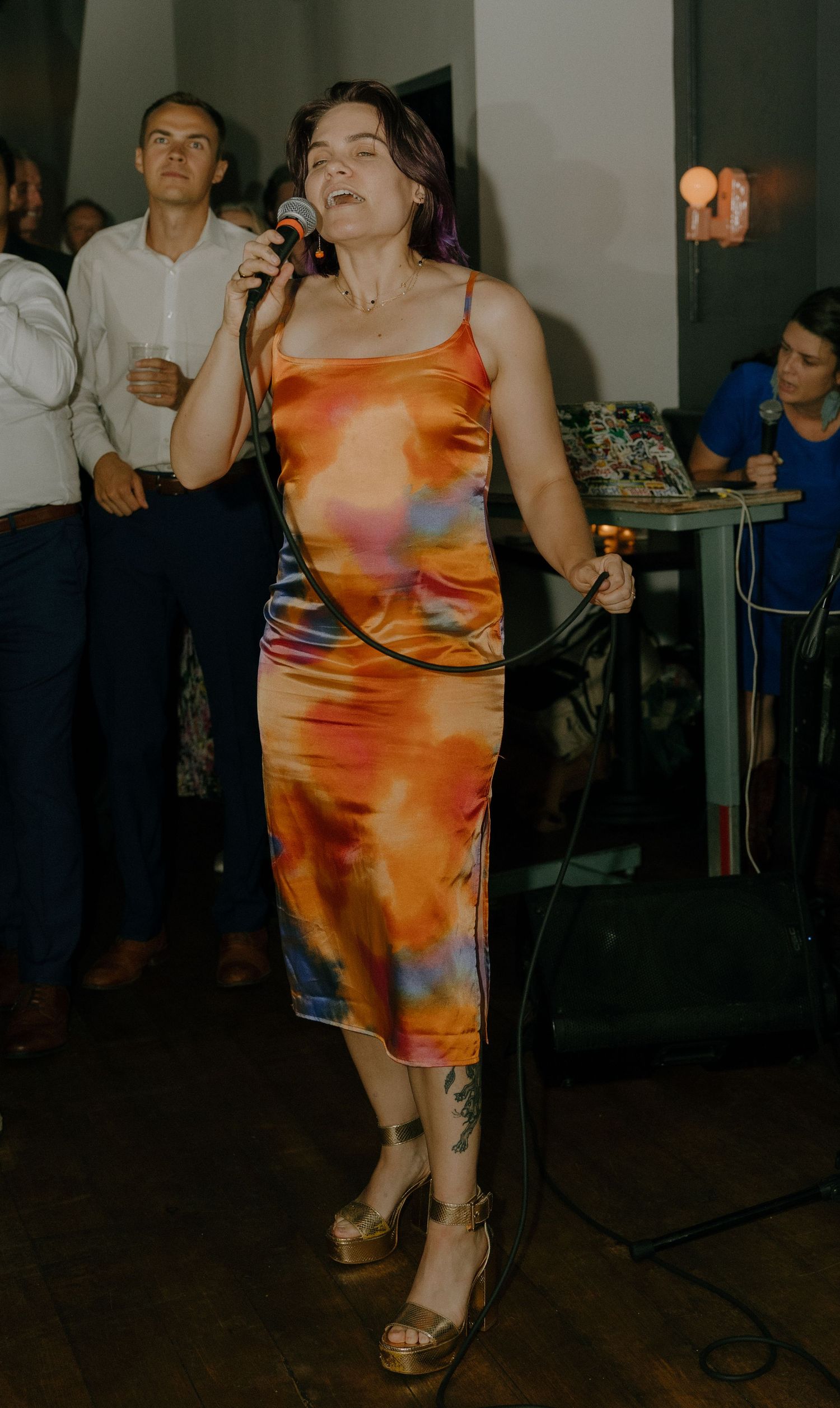 Person in a vibrant orange tie-dye dress dancing at a party.