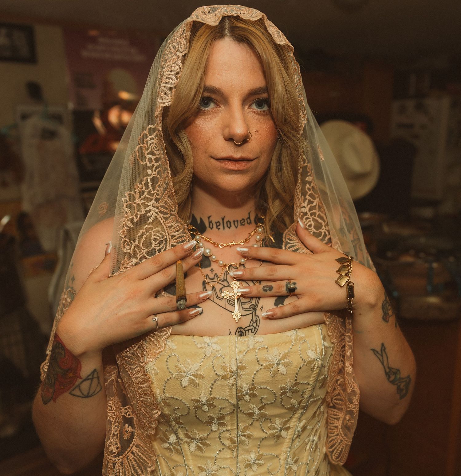 Person in a lace wedding dress with veil making expressive poses in an indoor setting.