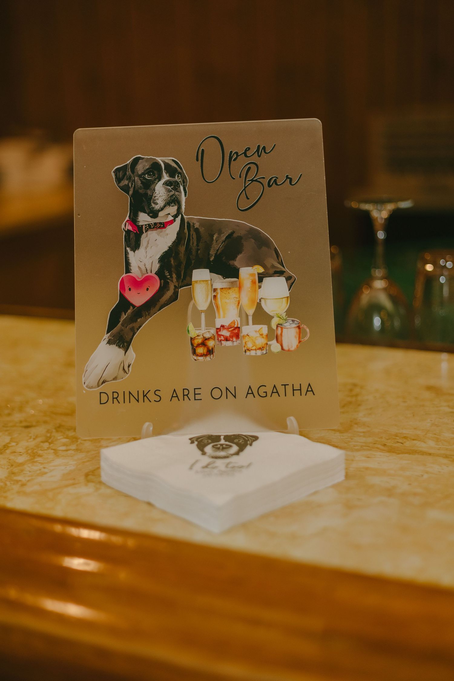 A series of decorative bar signs featuring an illustrated dog design and text 'Drinks are on Agatha' on wooden surfaces.
