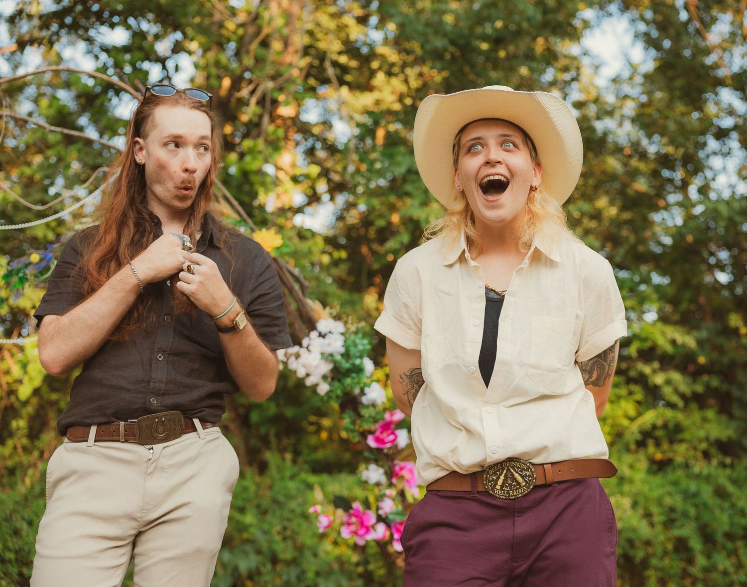 Wedding couple in vintage-inspired outfits posing playfully outdoors with autumn trees in background.