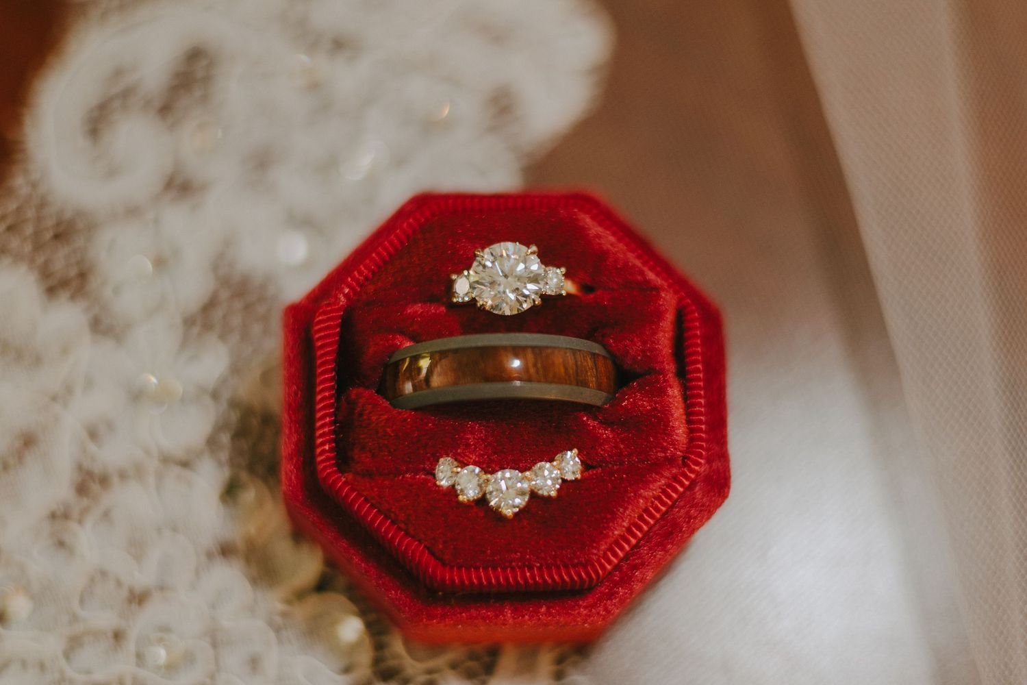 A collection of vintage engagement rings displayed on red velvet ring boxes against a light textured background.