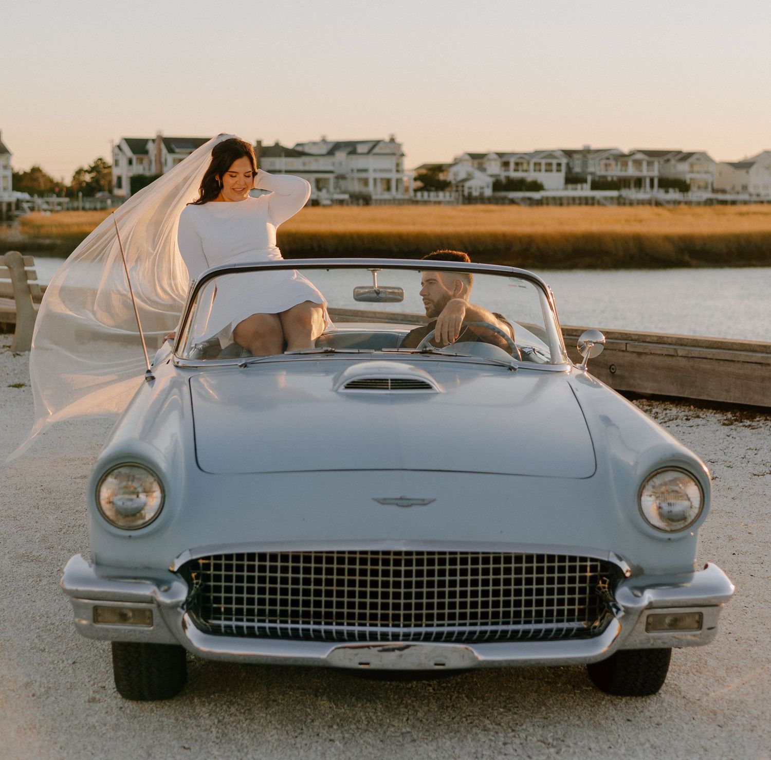 Front view details of a pristine white 1950s Ford Thunderbird classic car against sunset sky.