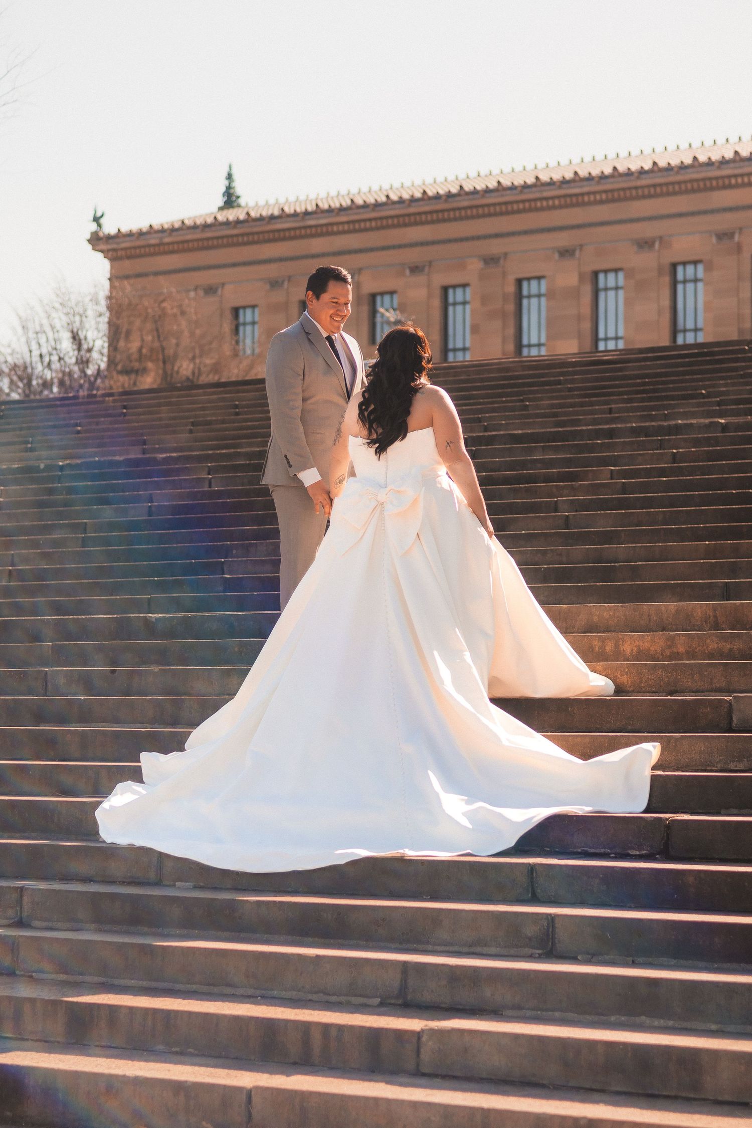 Sunlit wedding photos on dramatic stone steps with lens flare effects.