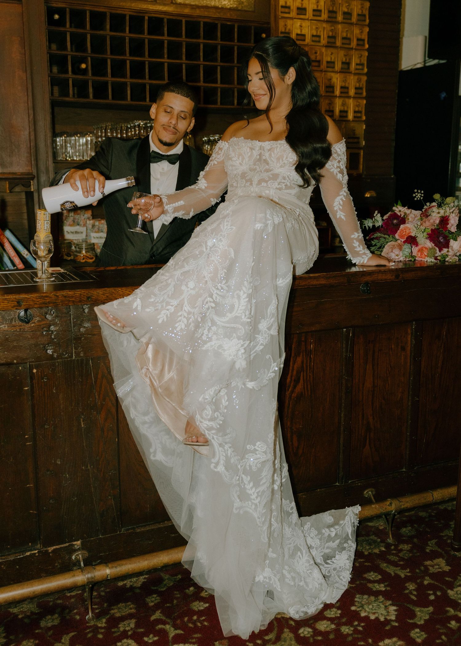 A wedding celebration moment captured in a rustic bar setting with wooden paneling and vintage decor.