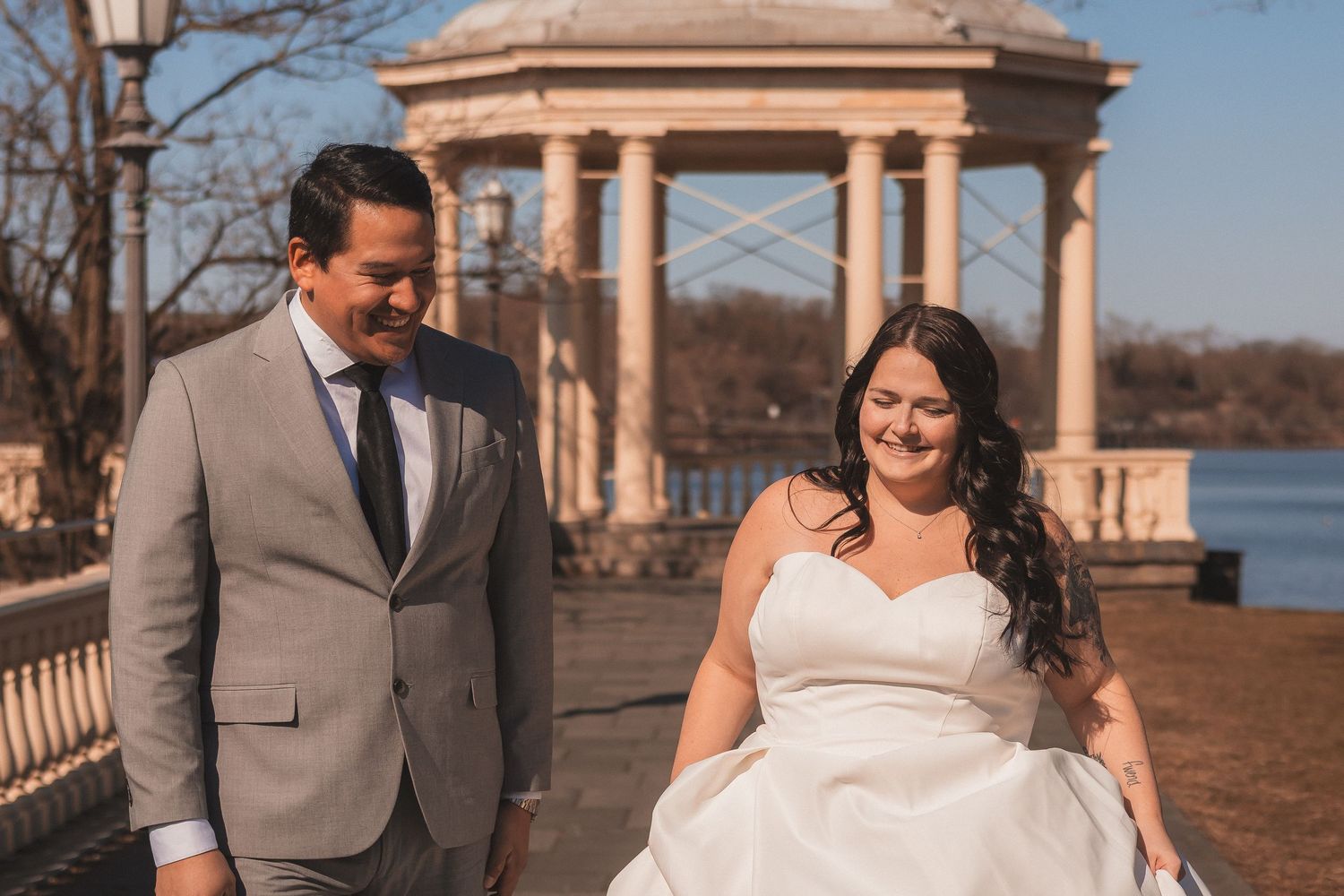 Candid wedding moments captured at an elegant stone pavilion overlooking water.