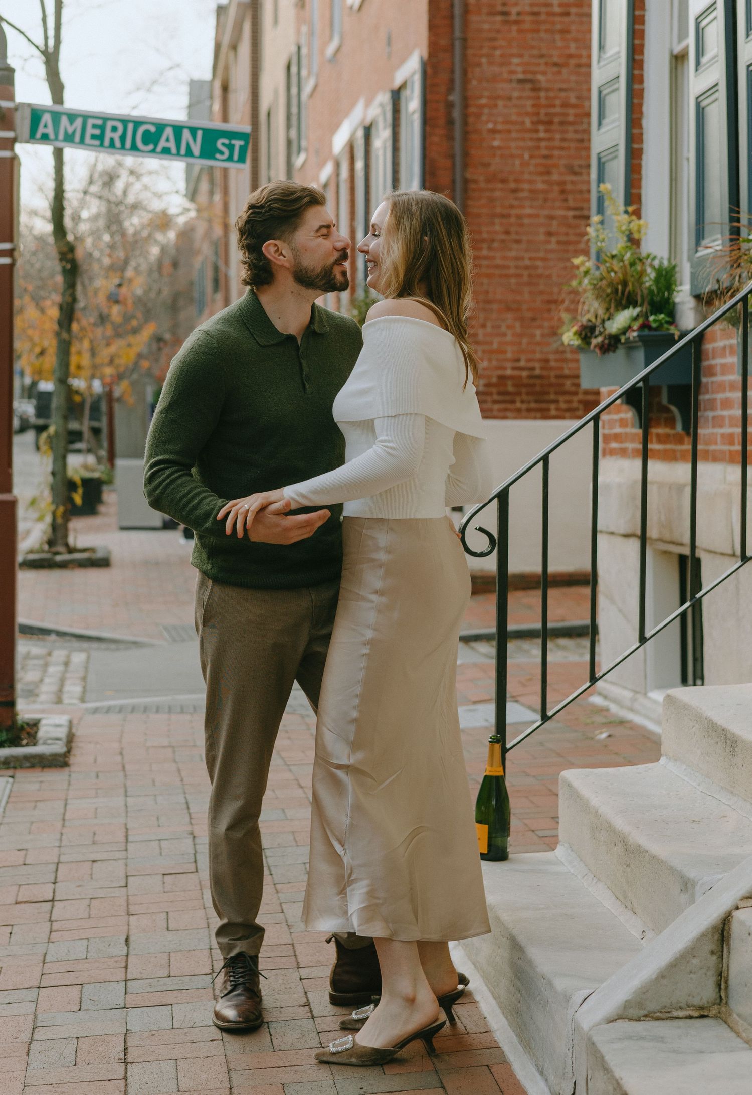 A tender moment shared on brick steps along an urban street with American Street sign visible.
