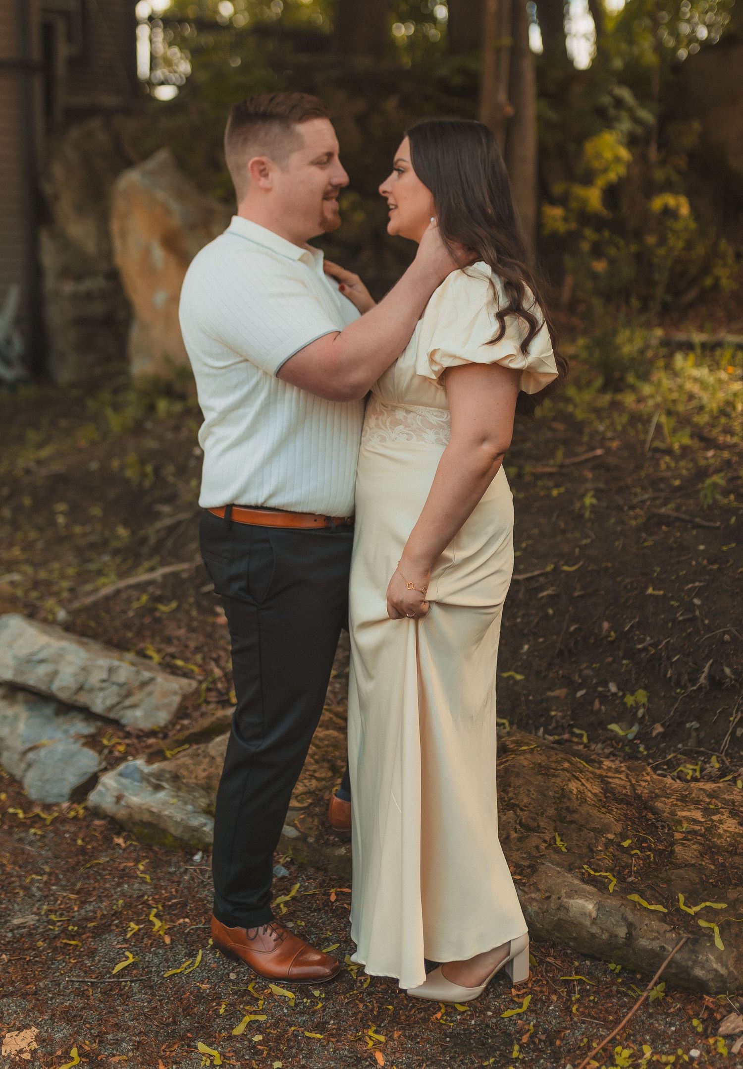A couple shares an intimate outdoor moment in front of autumn foliage.