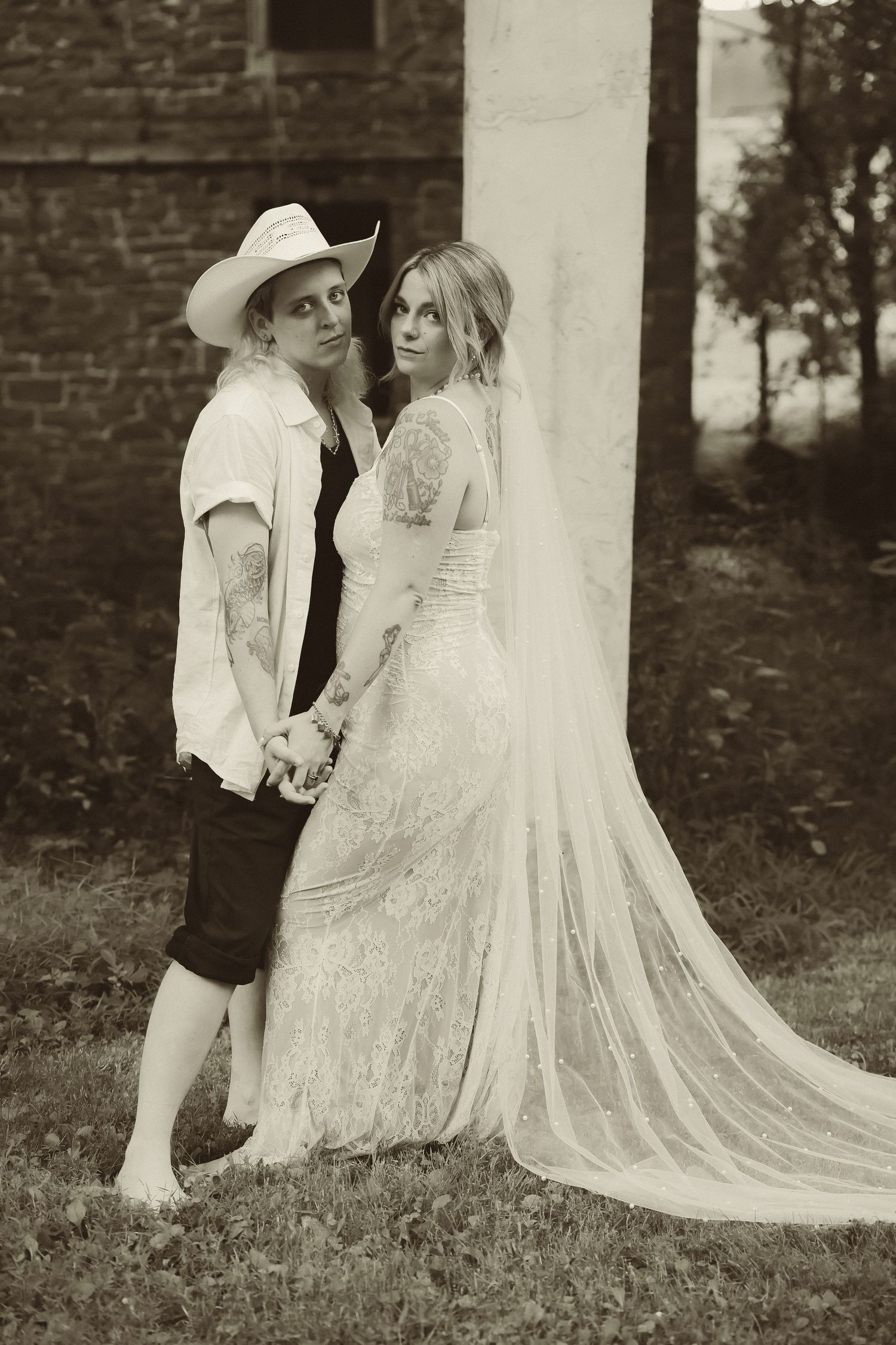 A romantic black and white wedding portrait against a brick wall background.
