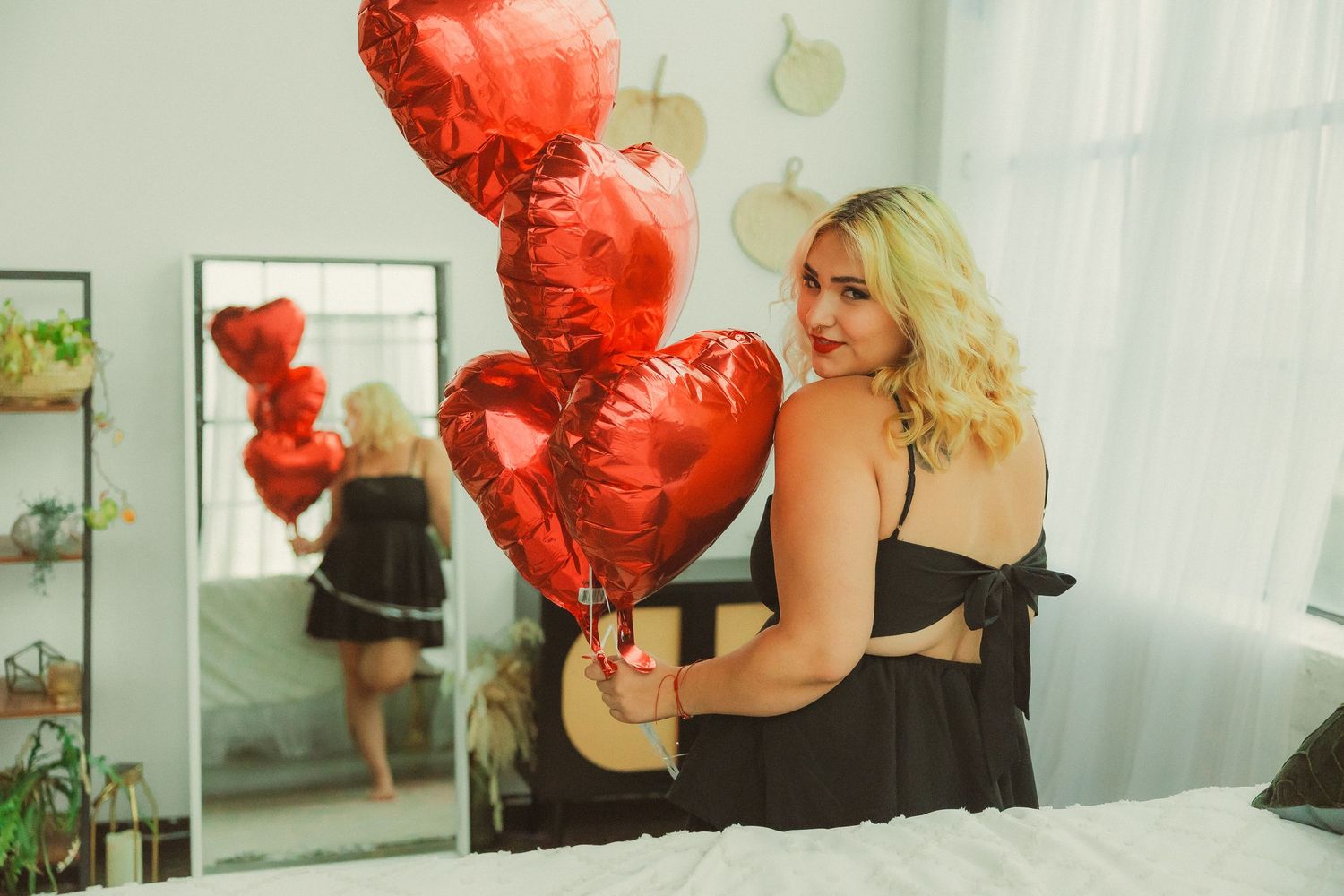 Romantic photo series with red heart-shaped balloons and white curtained windows.